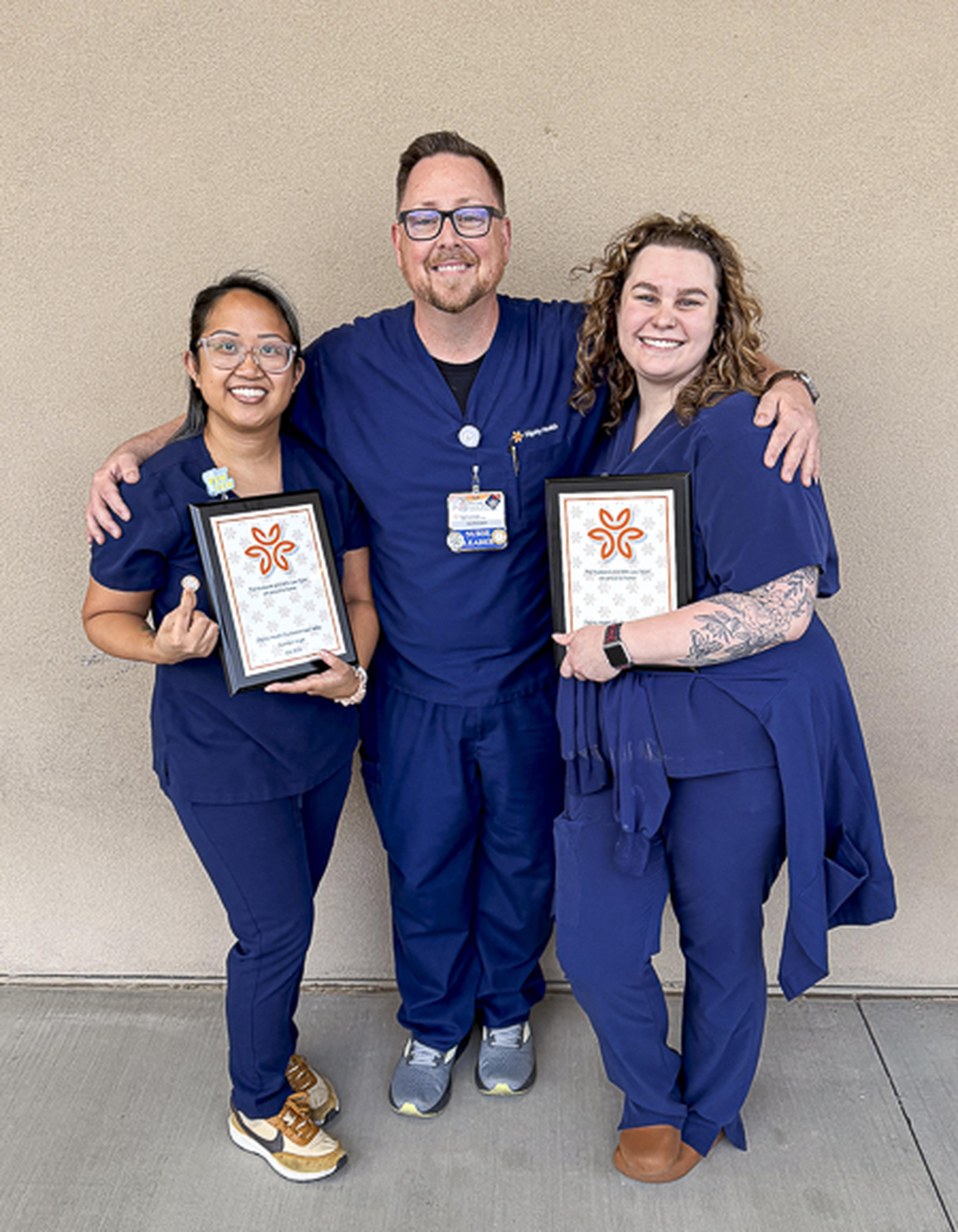 Three nurses at Chandler Regional Medical Center proudly display their Guardian Angel Awards, celebrating their dedication to compassionate patient care and service.