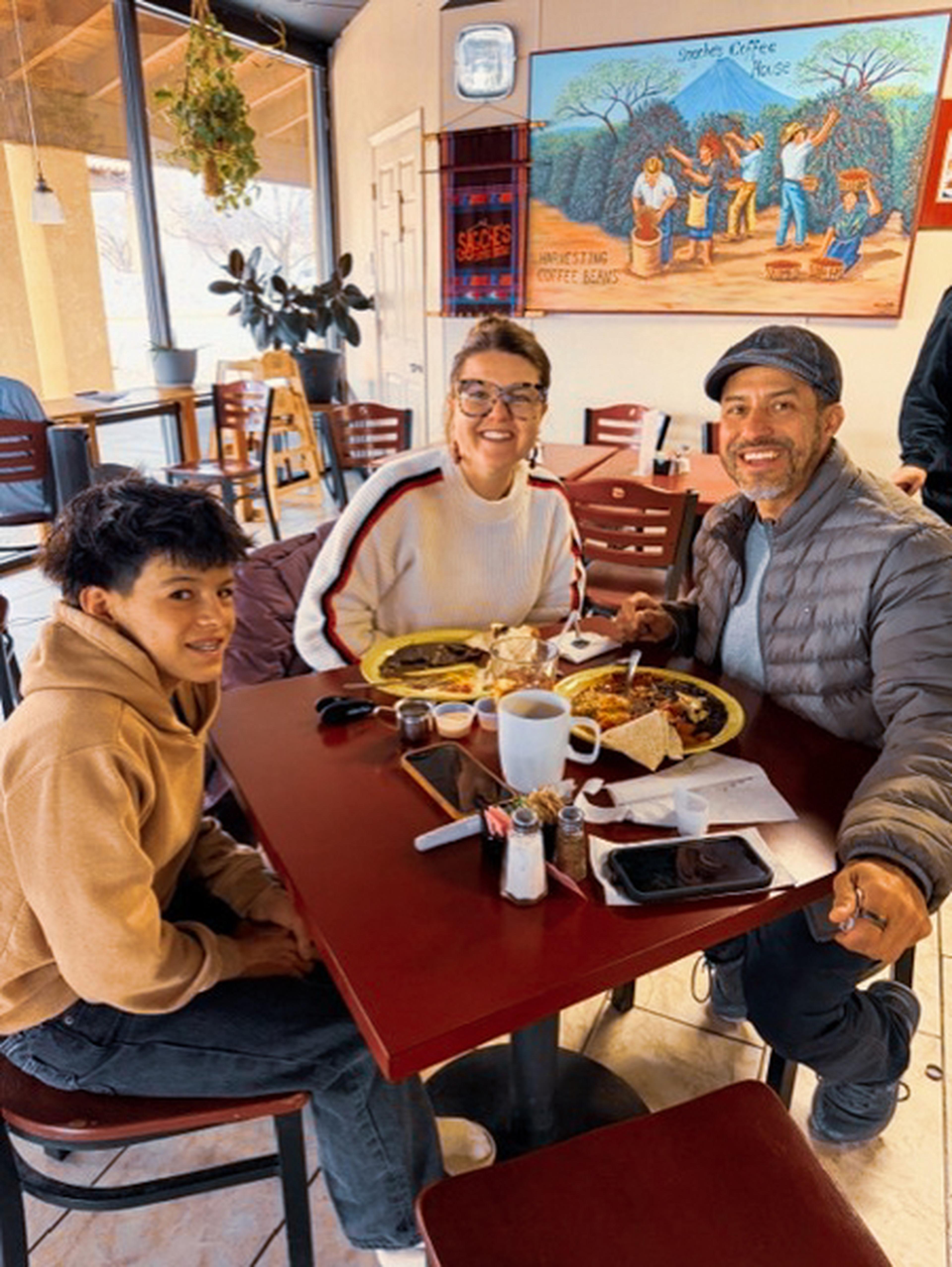 A smiling family of three enjoys their meal at Sagches’ Café in Santa Fe, NM, with drinks