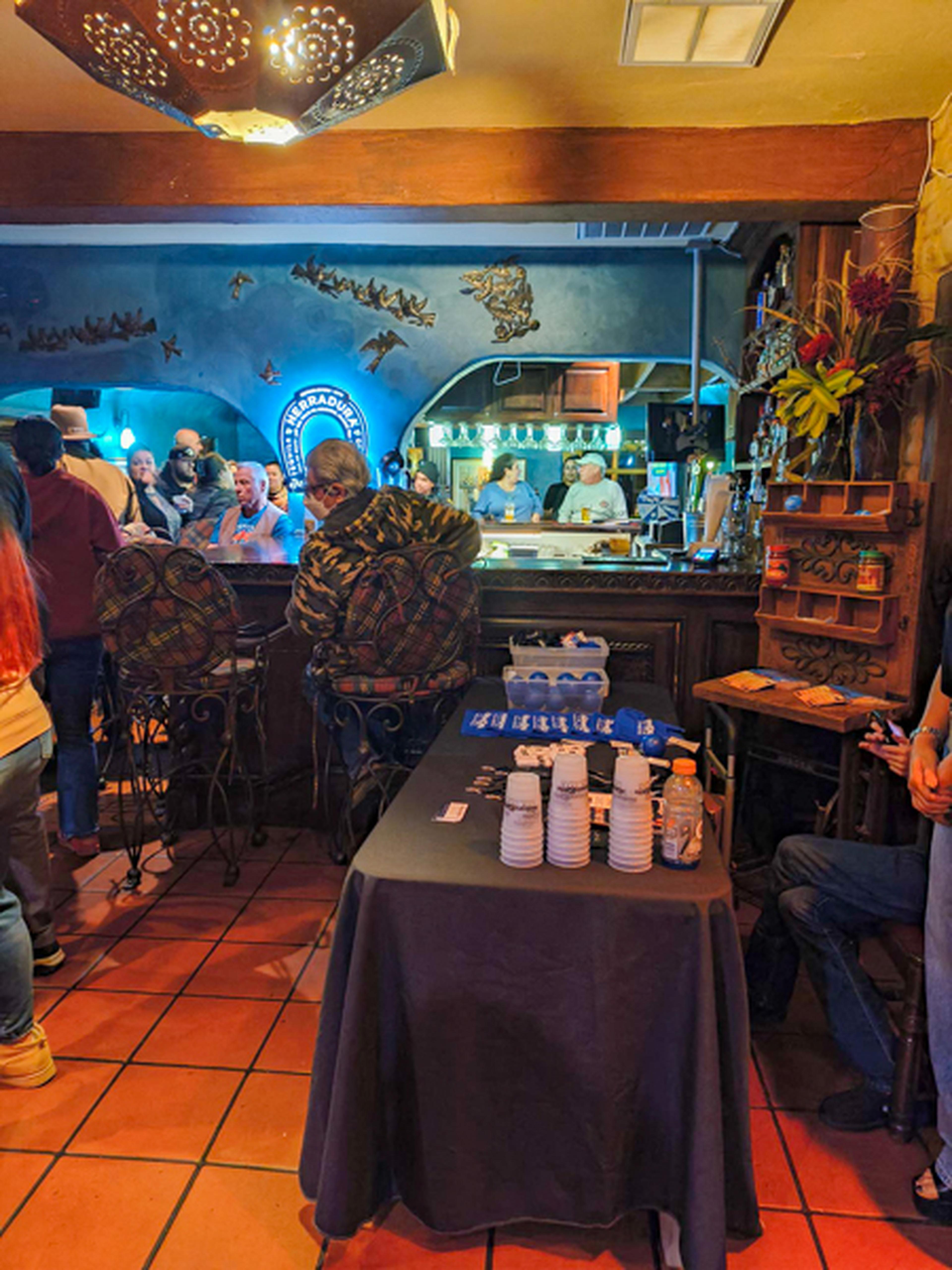A table with giveaway items, and people in the restaurant for an event