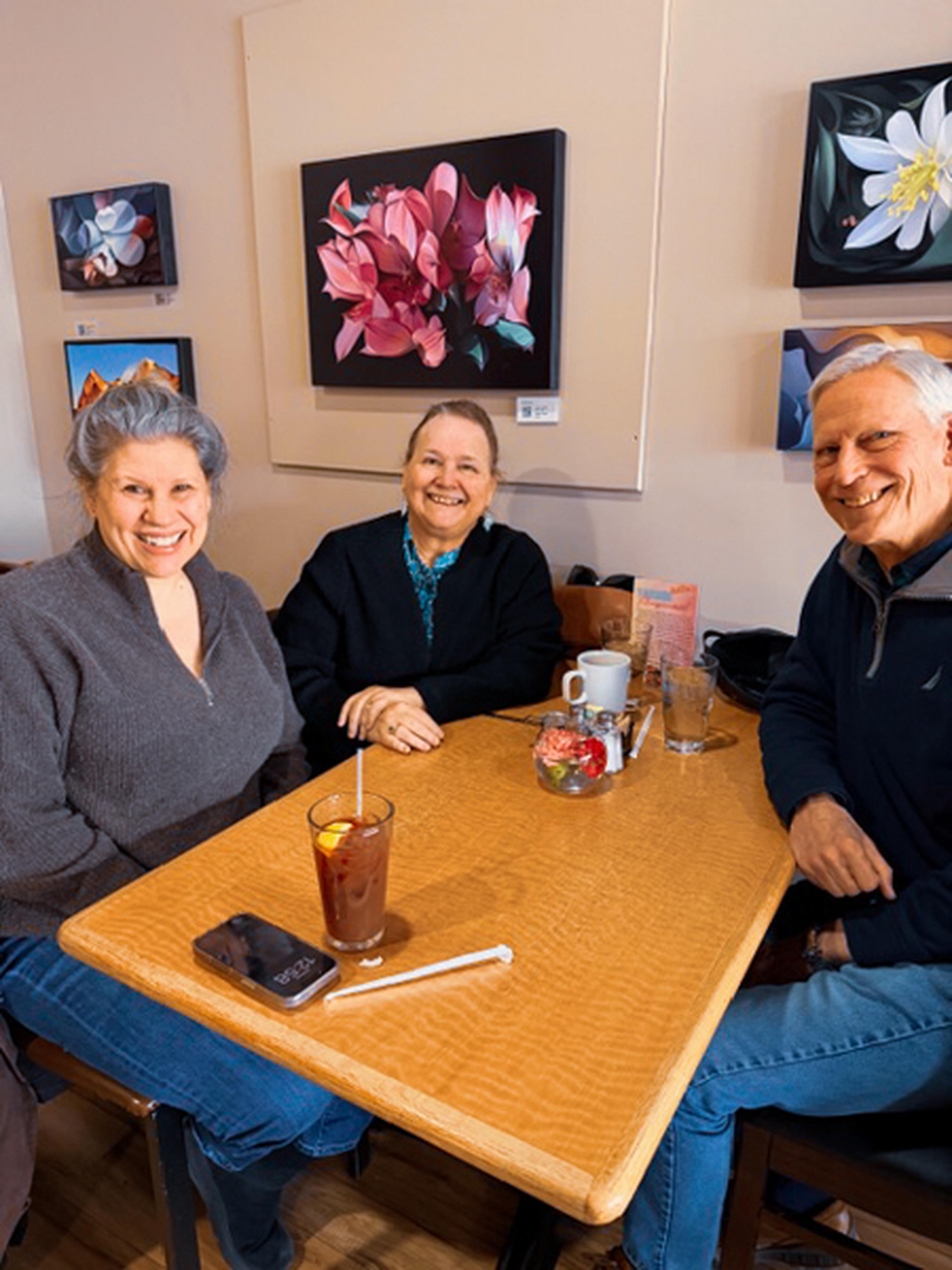 Three smiling customers relax at a wooden table at Sagches’ Café in Santa Fe, NM