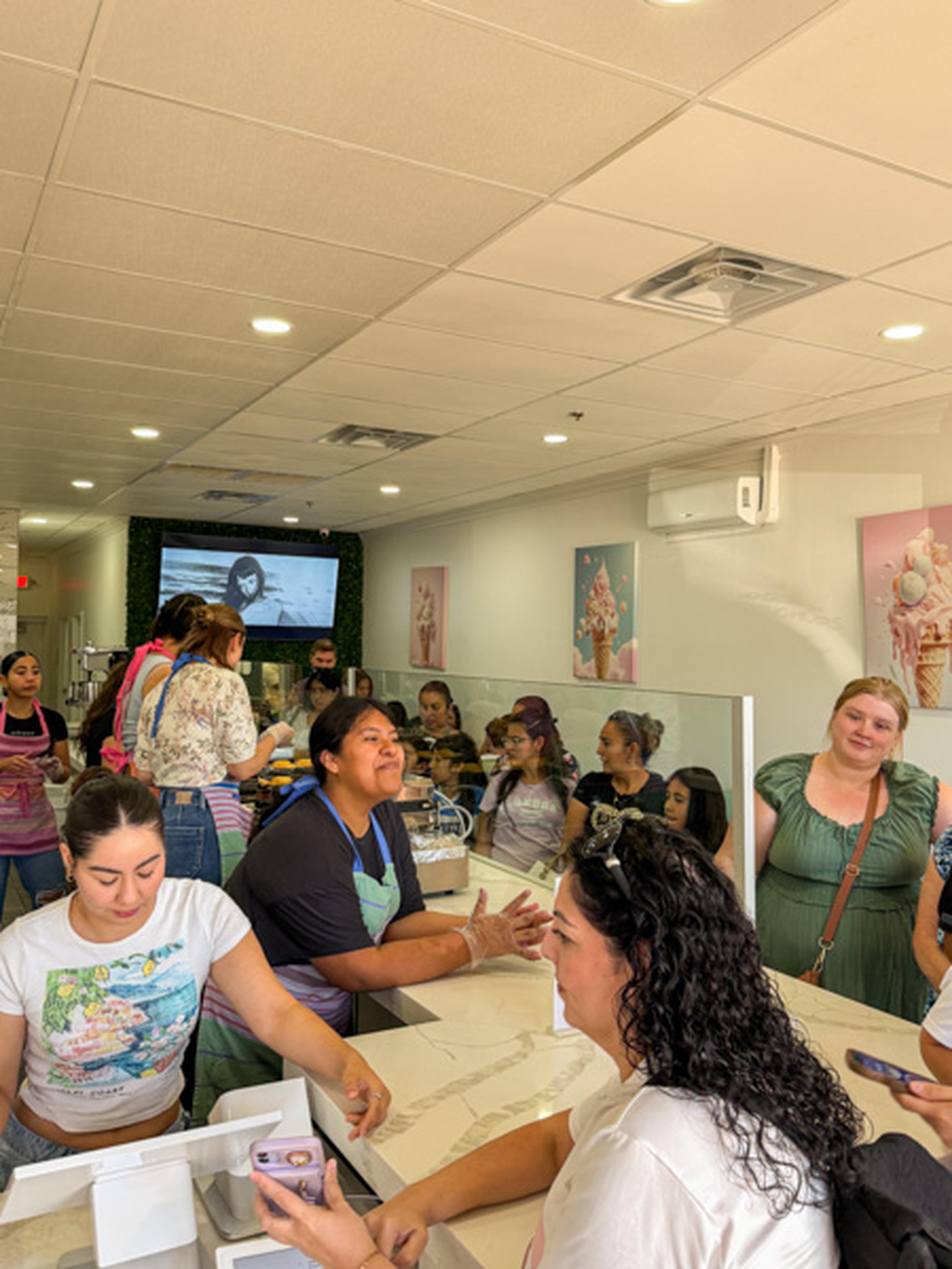 People gathered inside a HEART event in Peoria at Iced Out Ice Cream, chatting and ordering at the counter, with colorful ice cream art on the walls.