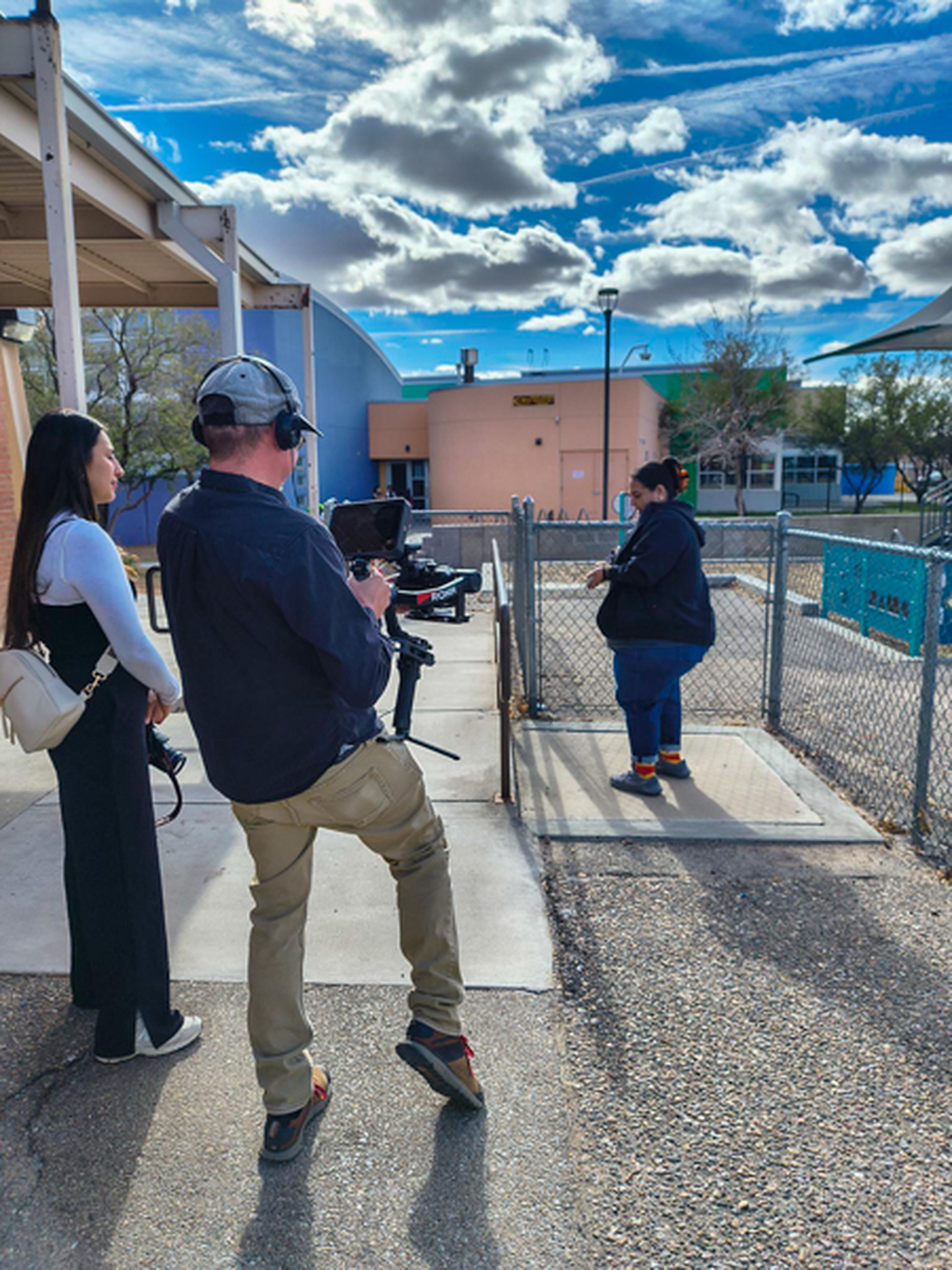 Video crew following teacher as she prepares to pose for a photo