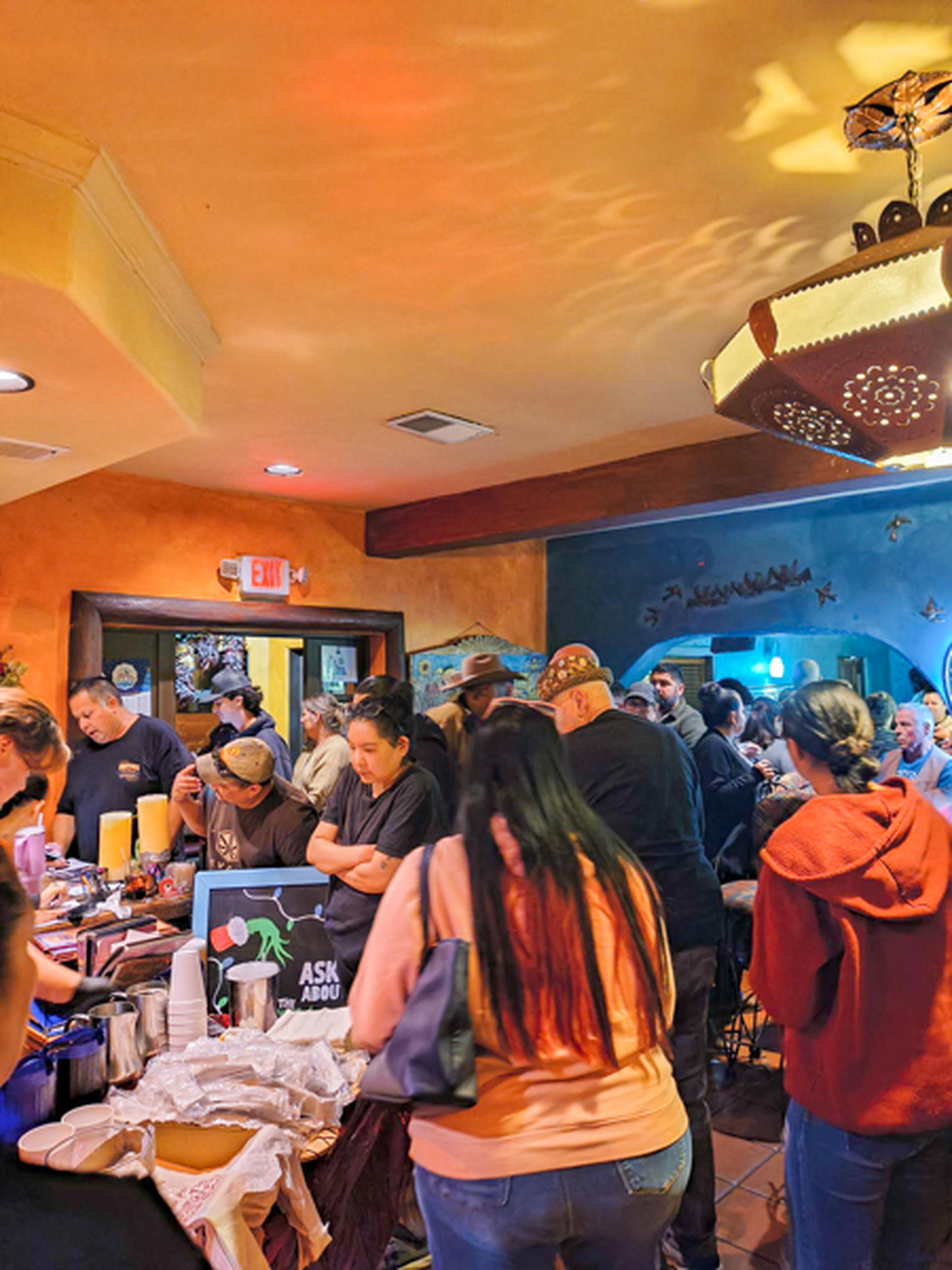 A vibrantly colored restaurant full of people, mostly standing or at