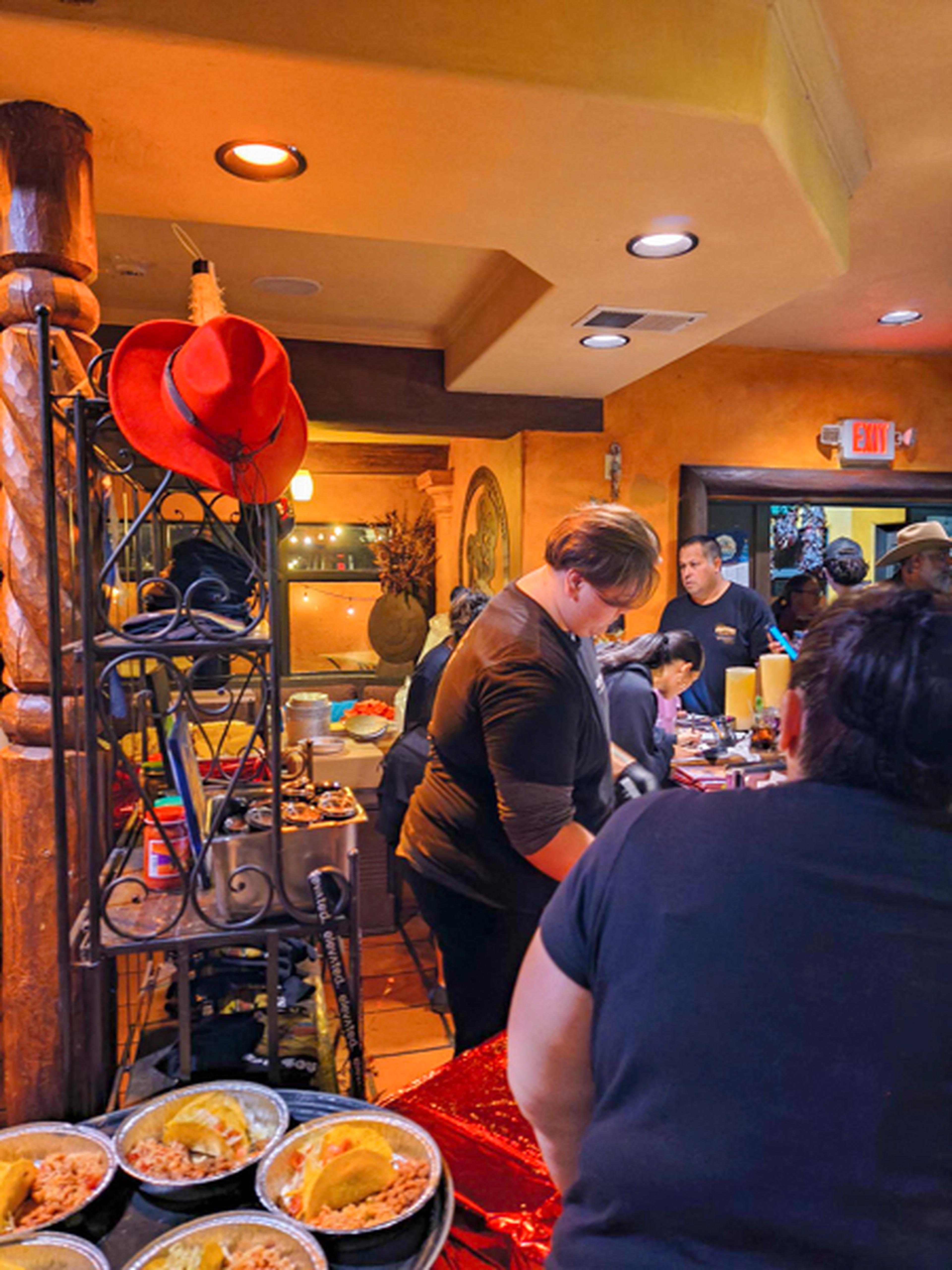 The service side of a bar with food being prepared and a red cowgirl hat