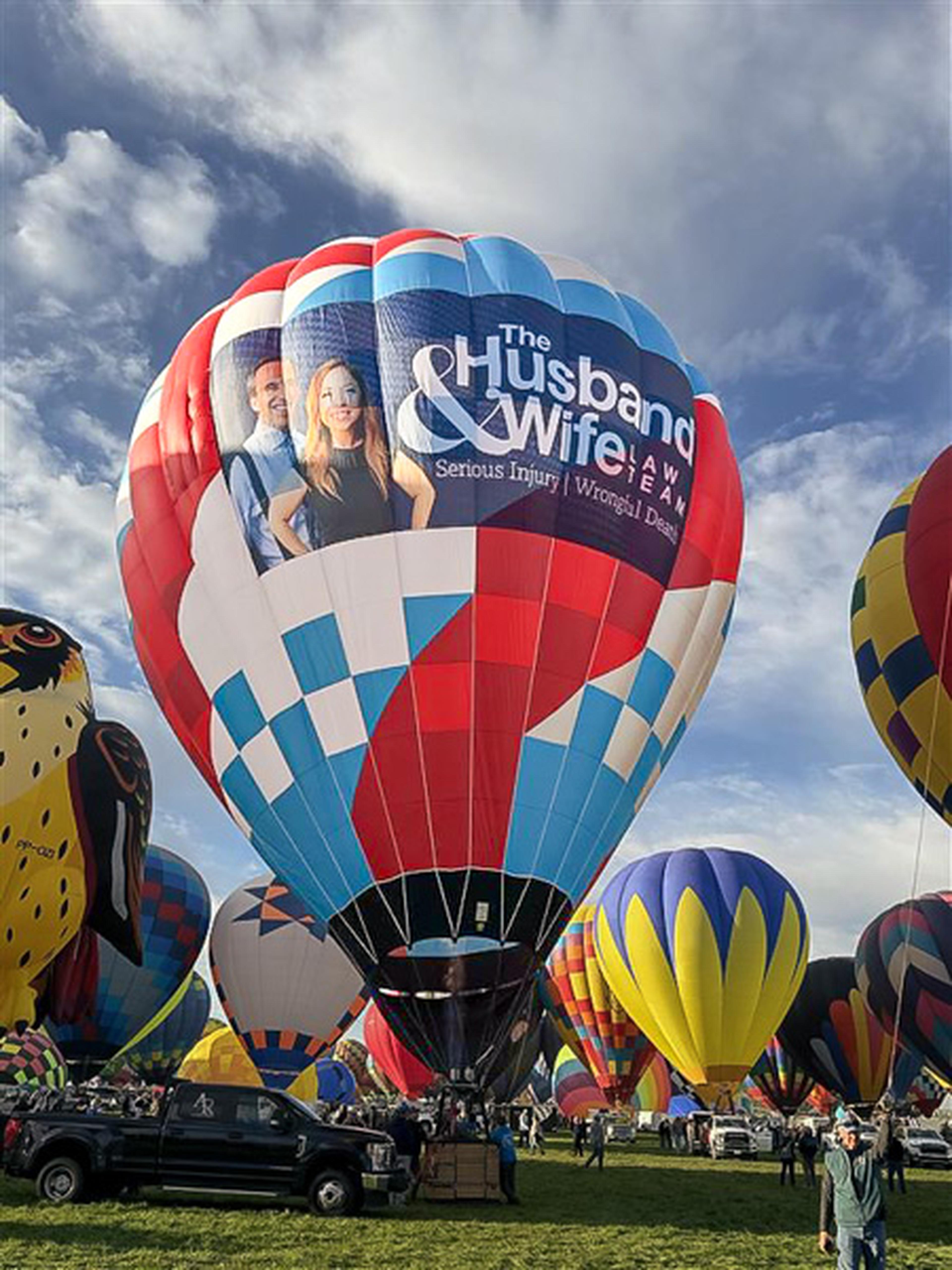 Mark and Alexis Breyer take to the Albuquerque skies as the colorful Husband & Wife Law Team balloon stands out among the Balloon Fiesta crowd.