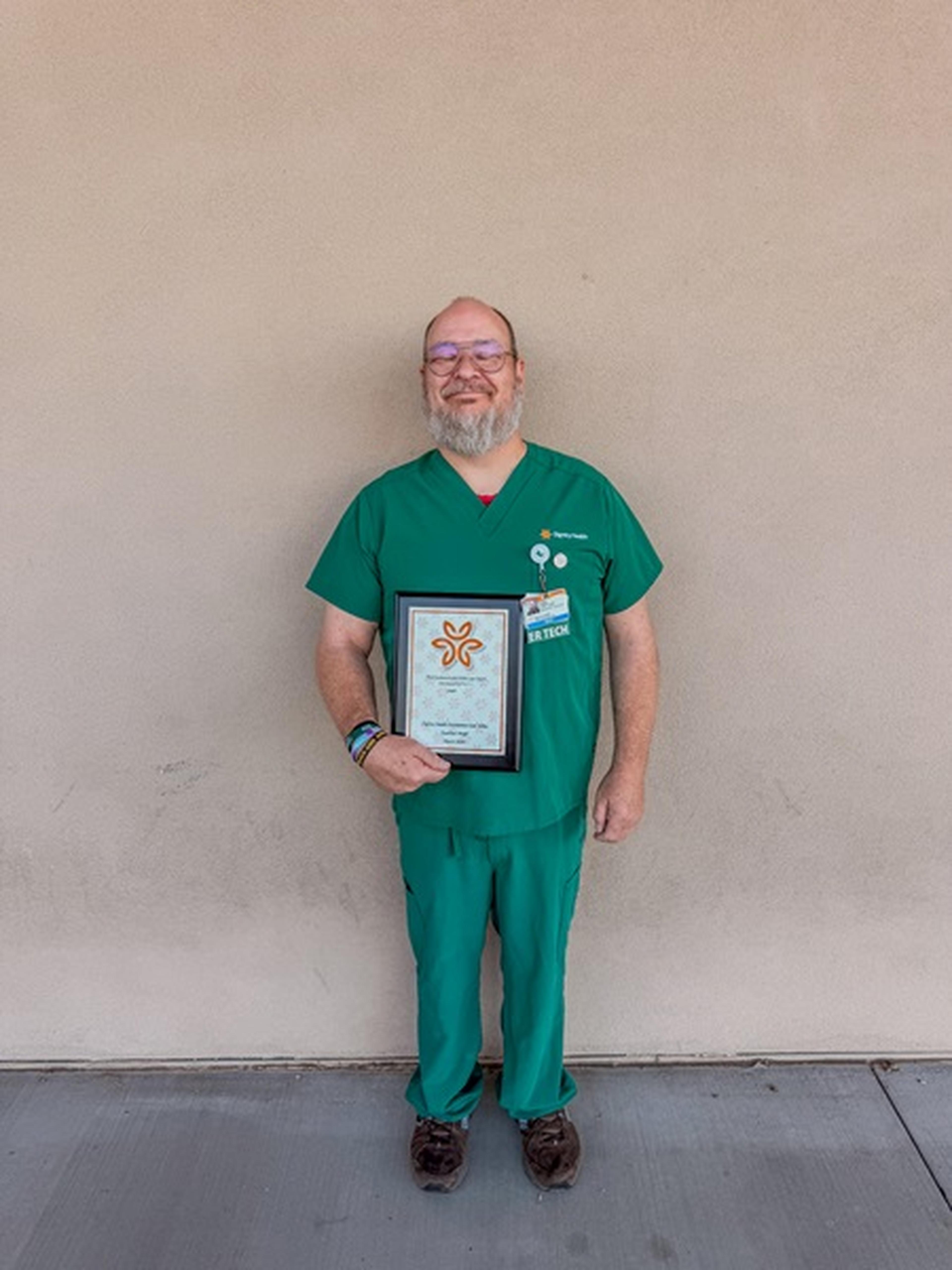 Nurse Jody Celebrated with Guardian Angel Award, standing against a plain wall.
