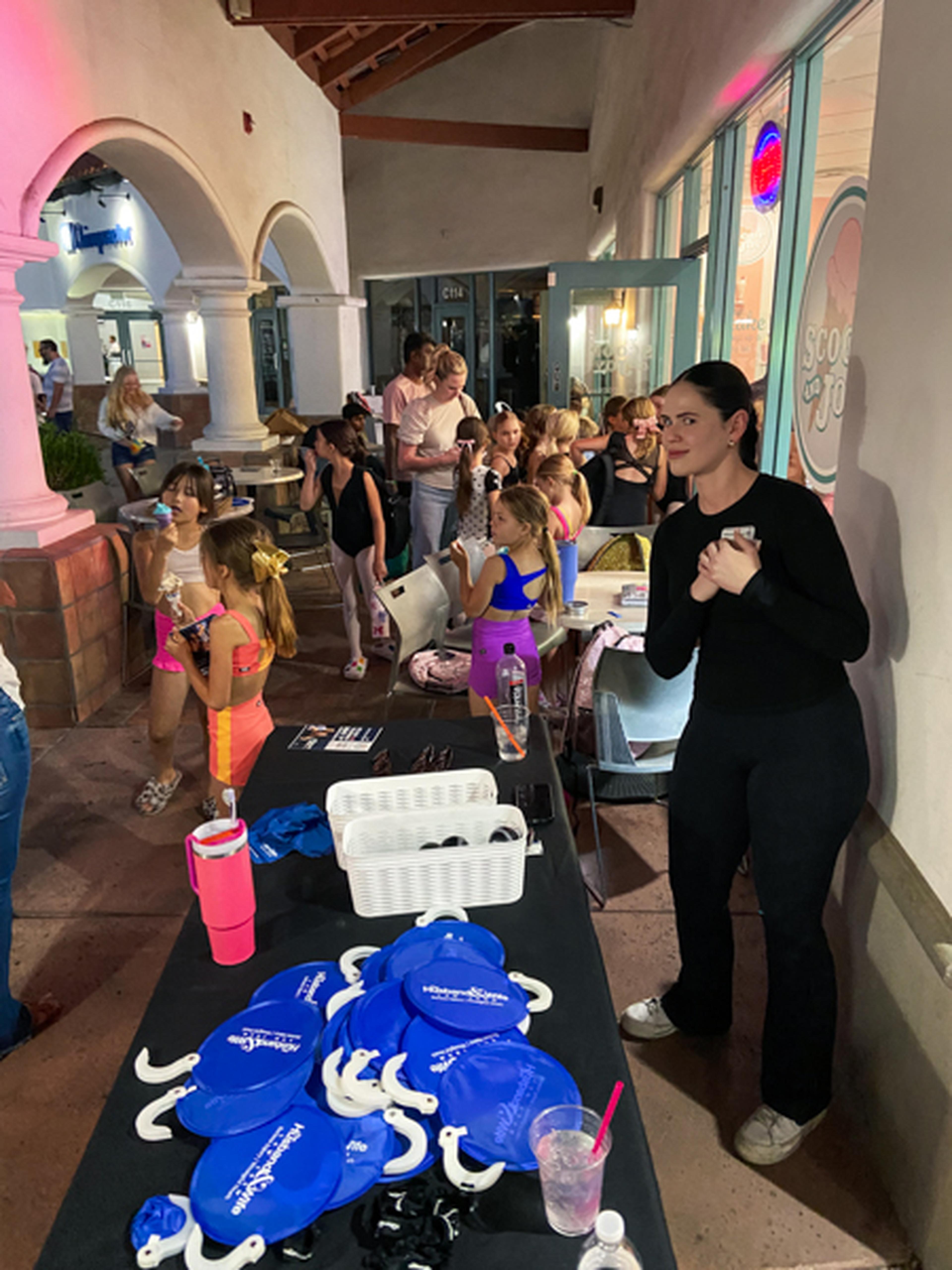 A group of people, including children, gather outside with a table displaying Husband & Wife Law Team promotional items.