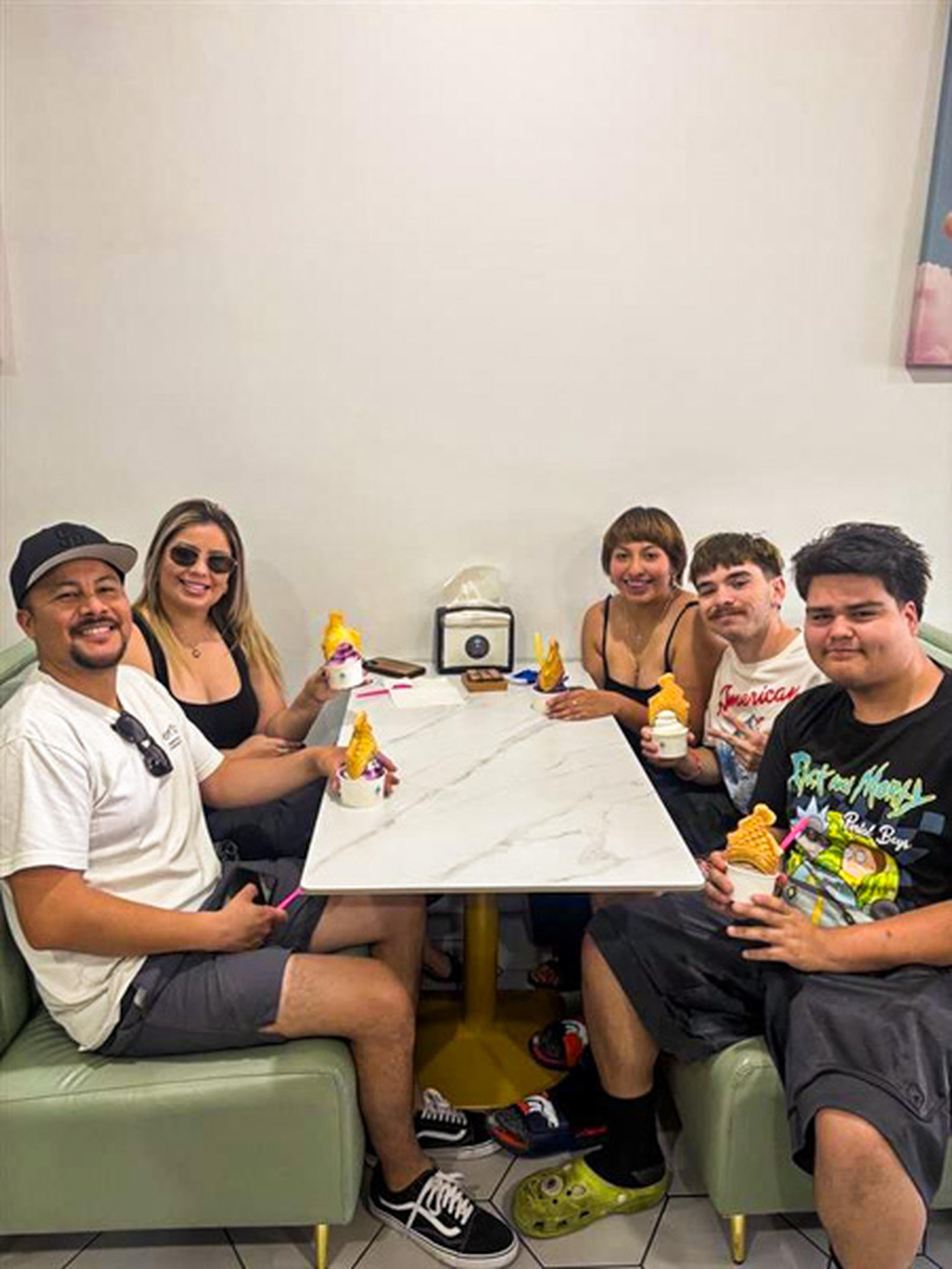 At a bright, welcoming Iced Out Ice Cream table, five friends laugh and dig into their topped‑up cones around a marble surface.