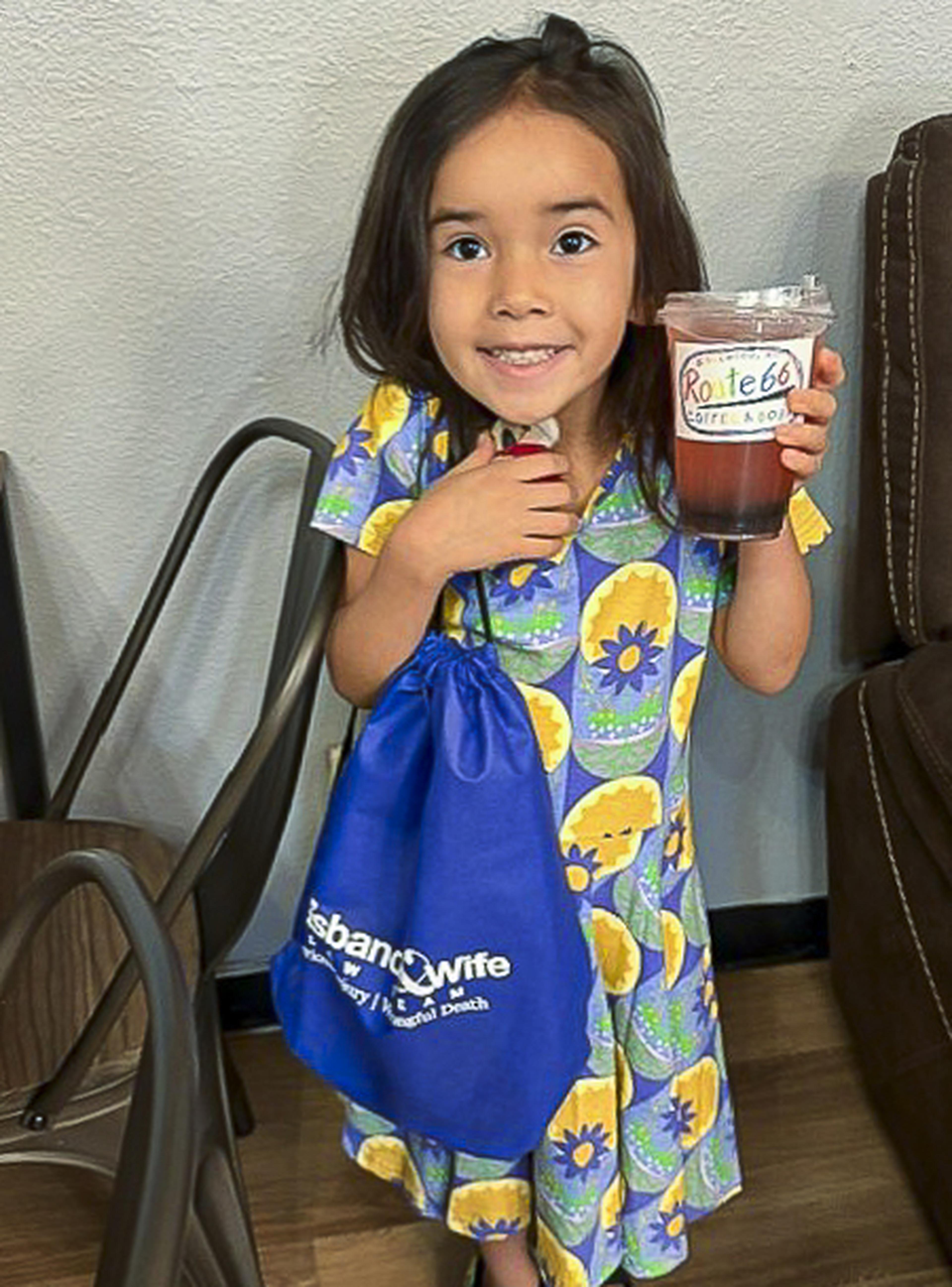 A smiling young girl shows off her Route 66 drink and Husband & Wife Law Team drawstring bag while enjoying a fun community event.
