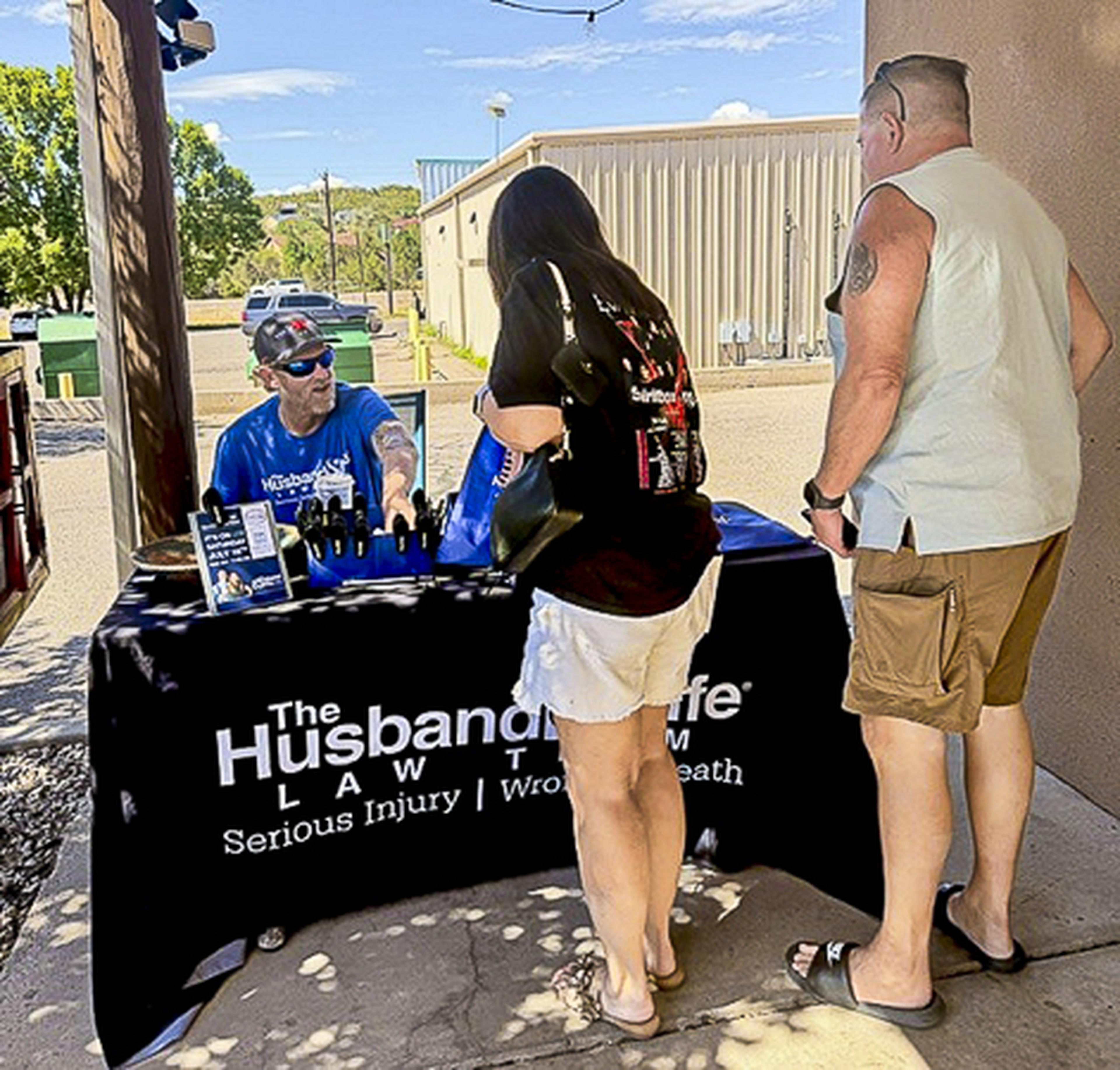 A Husband & Wife Law Team representative greets community members outside Route 66 Coffee & Boba Co., sharing information and giveaways during a local outreach event.
