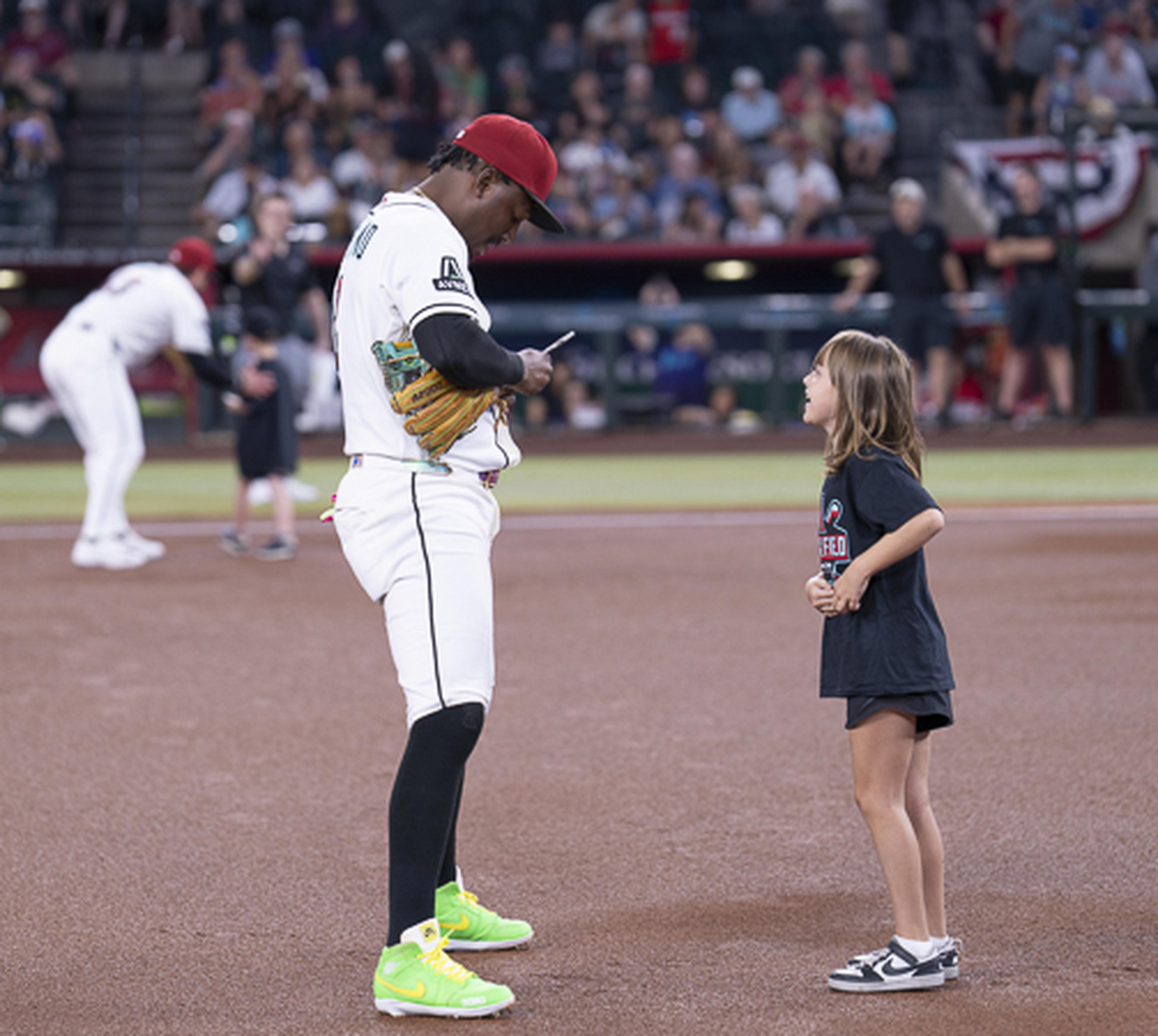 An Arizona Diamondbacks player signs an autograph for a young fan on the field, creating a memorable pregame experience at Chase Field.