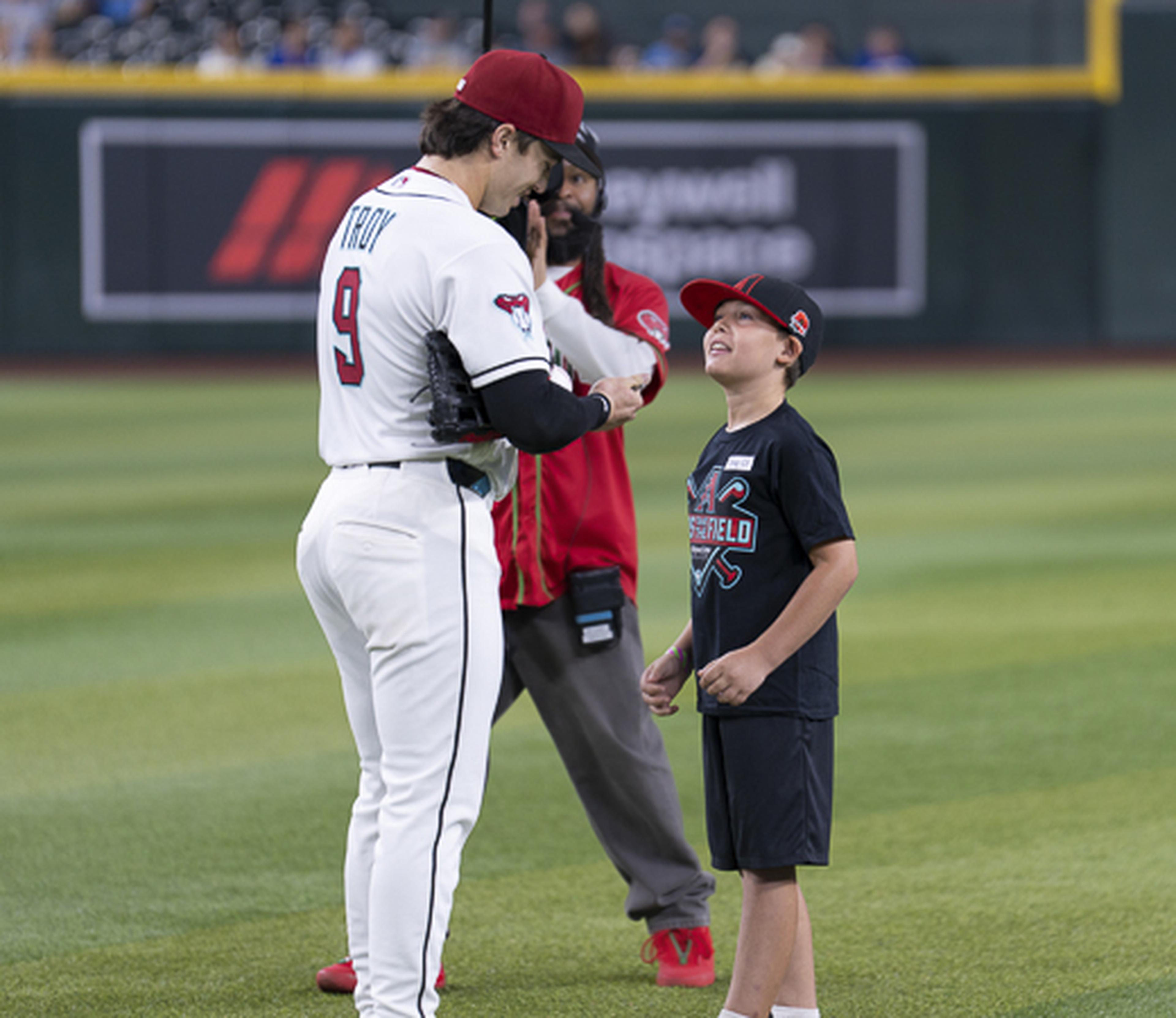 An Arizona Diamondbacks player shares a special moment with a young fan on the field, creating a memorable experience at the ballpark.