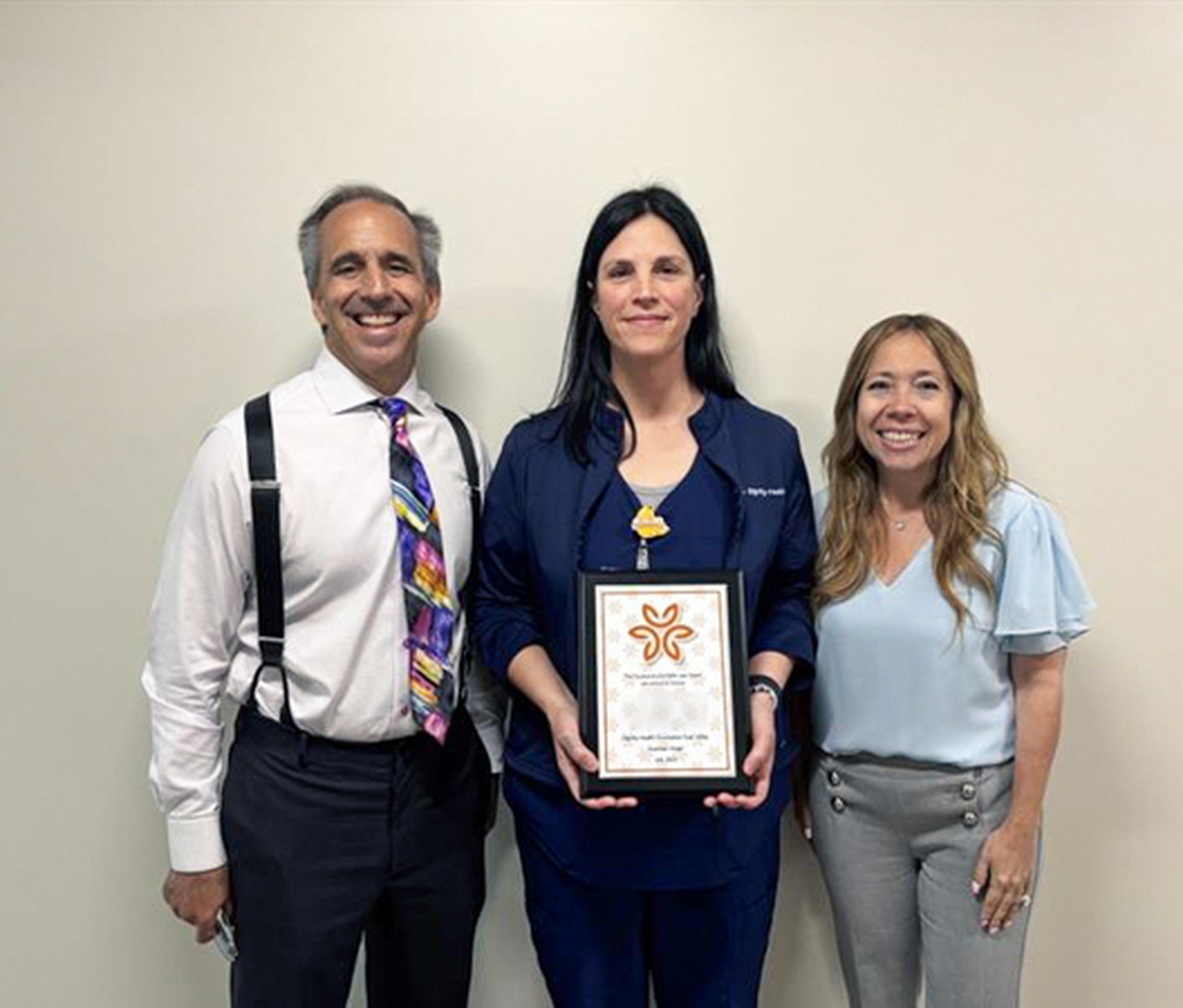 Nurse Sara displays her award with Mark and Alexis Breyer