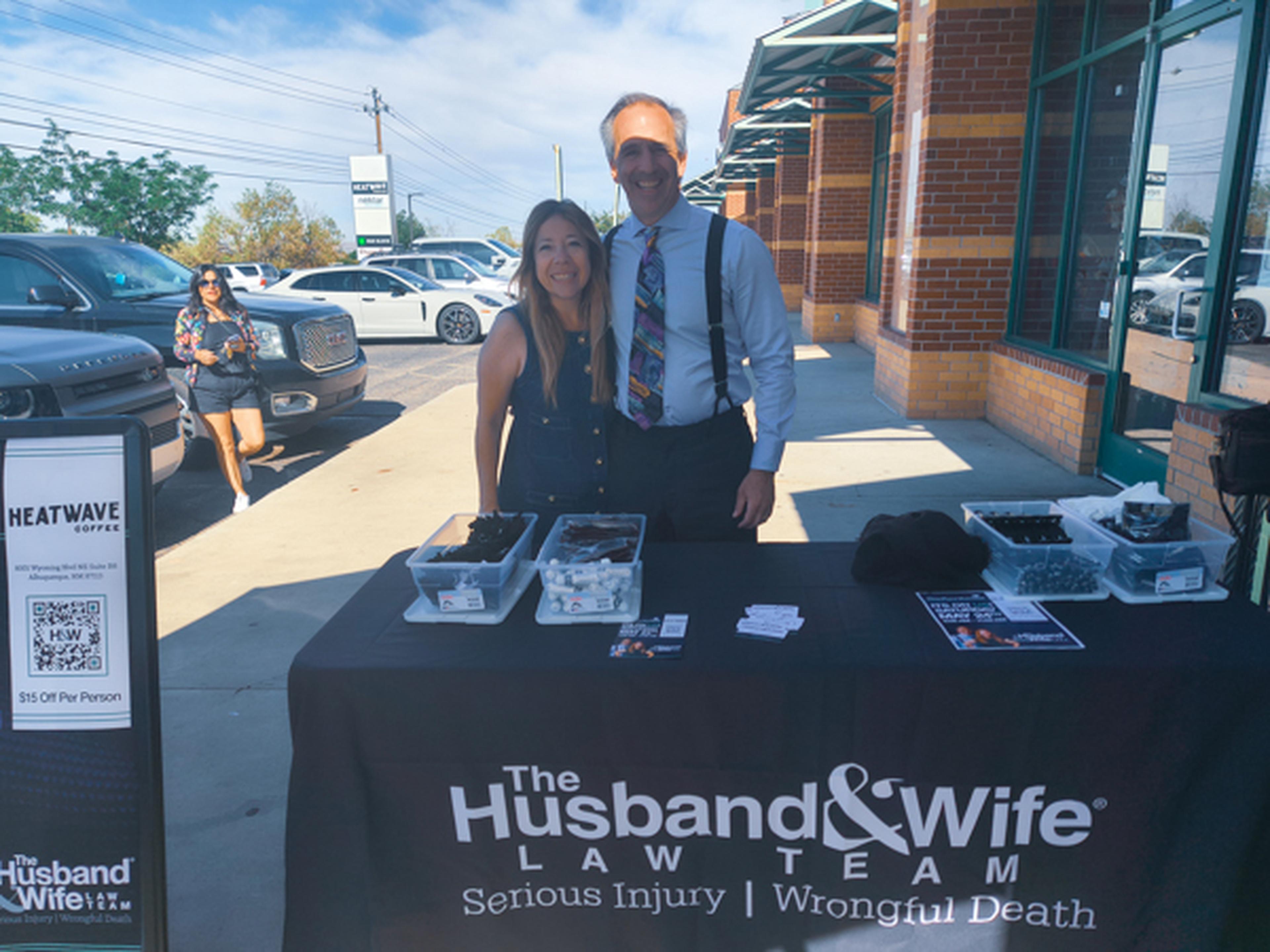 Mark and Alexis Breyer pose and smile for a photo behind a table with giveaway items