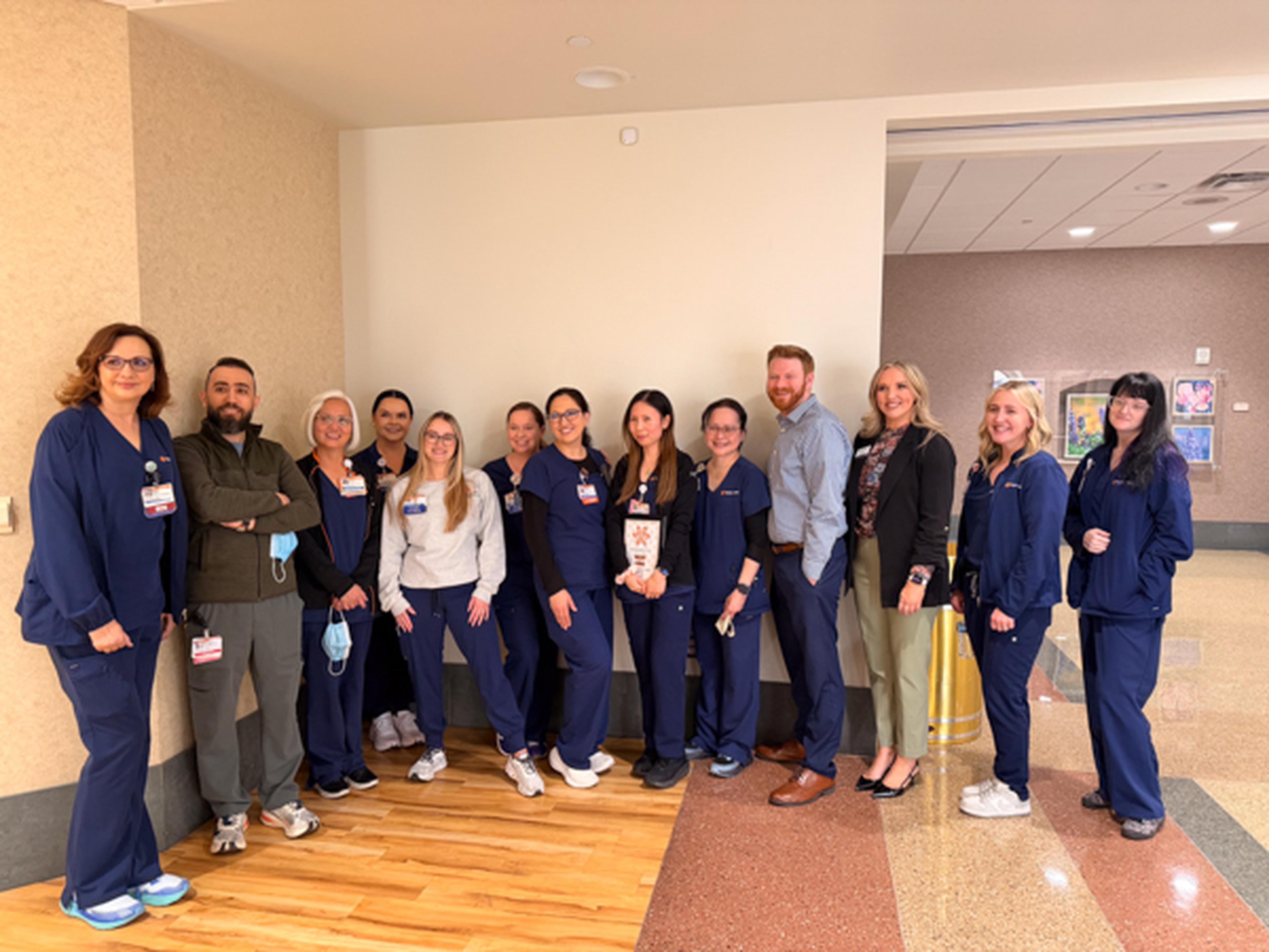A group of healthcare professionals in scrubs and formal attire with our award winner Vicky