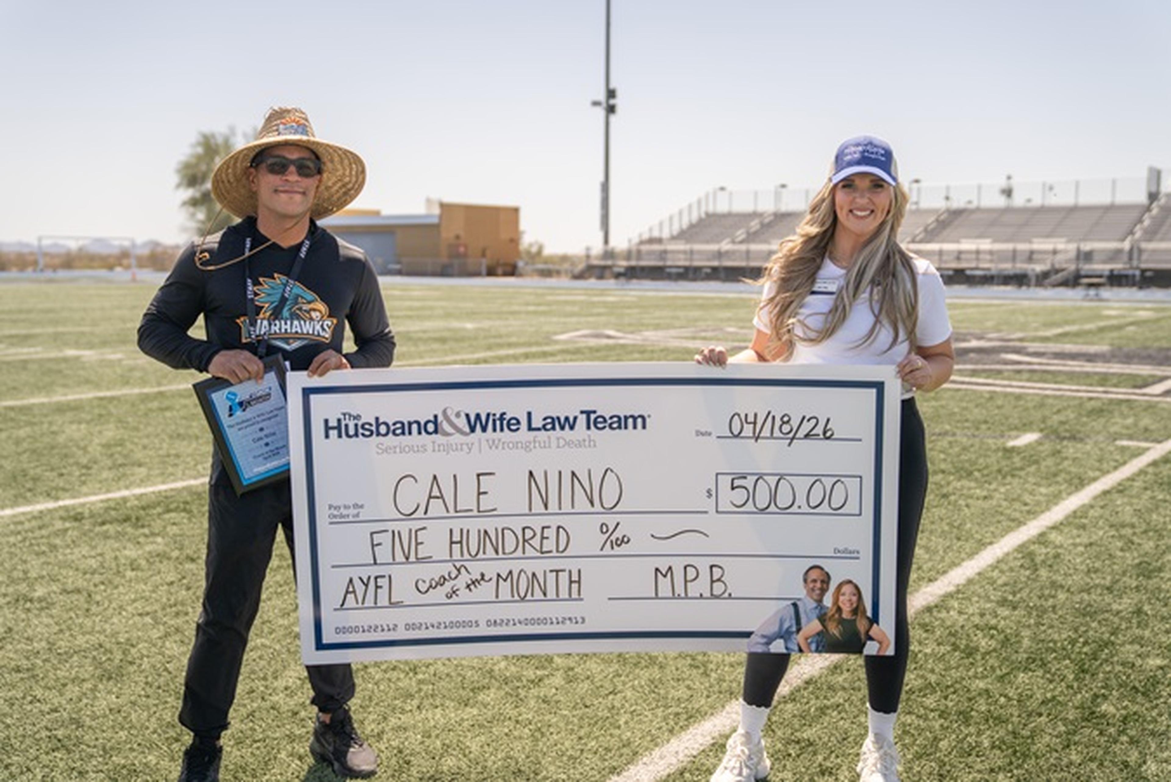 Jen from the Husband & Wife Law Team presents Coach Nino with a $500 AYFL Coach of the Month check.