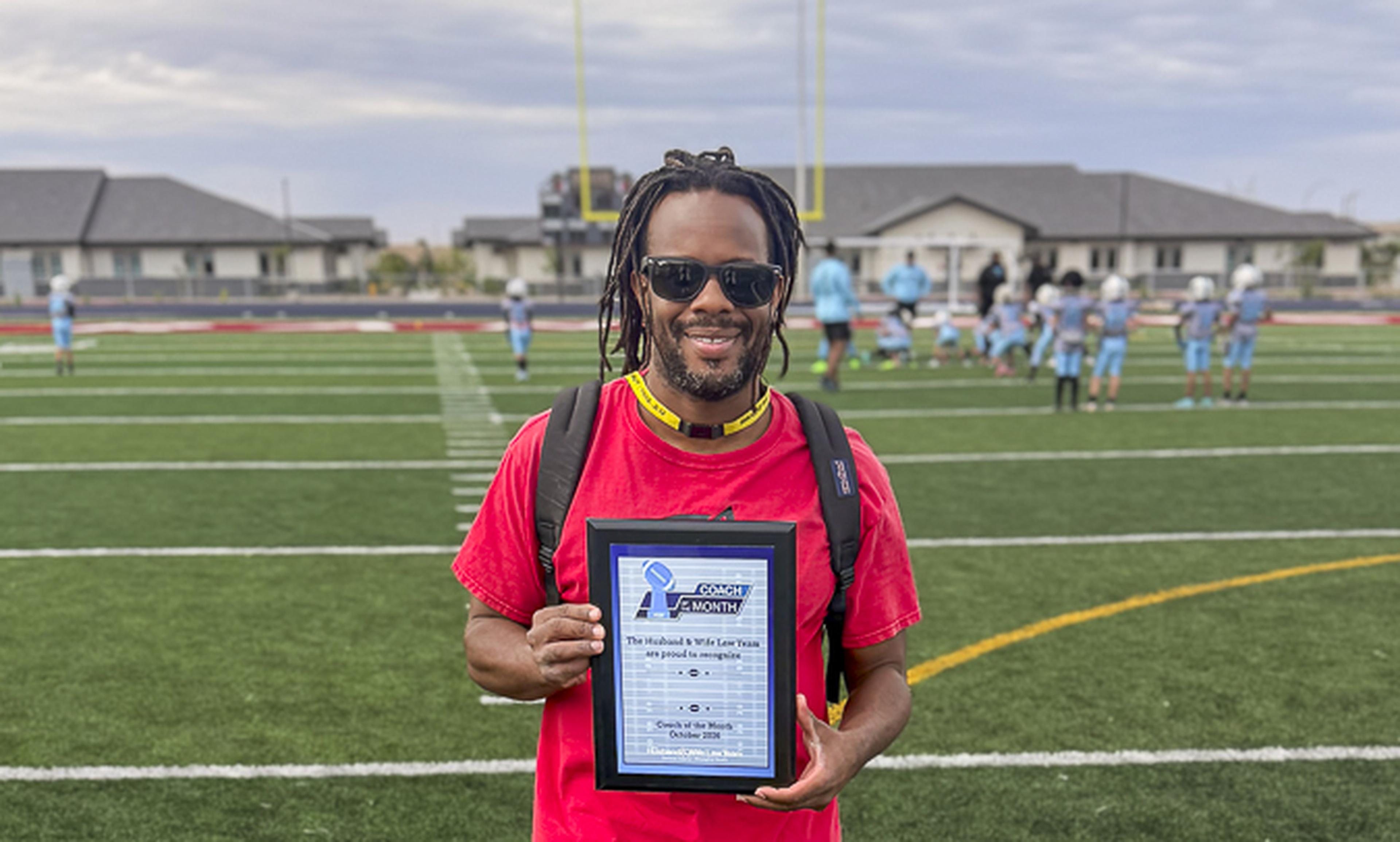 Celebrating an outstanding leader! Coach Edwards proudly accepts his Husband & Wife Law Team Coach of the Month recognition on the field.