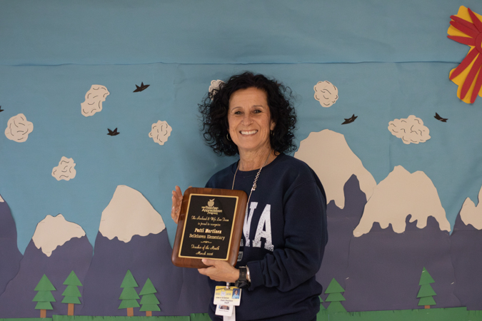 Ms. Martinez smiling and holding a Teacher Appreciation Award from The Husband & Wife Law Team