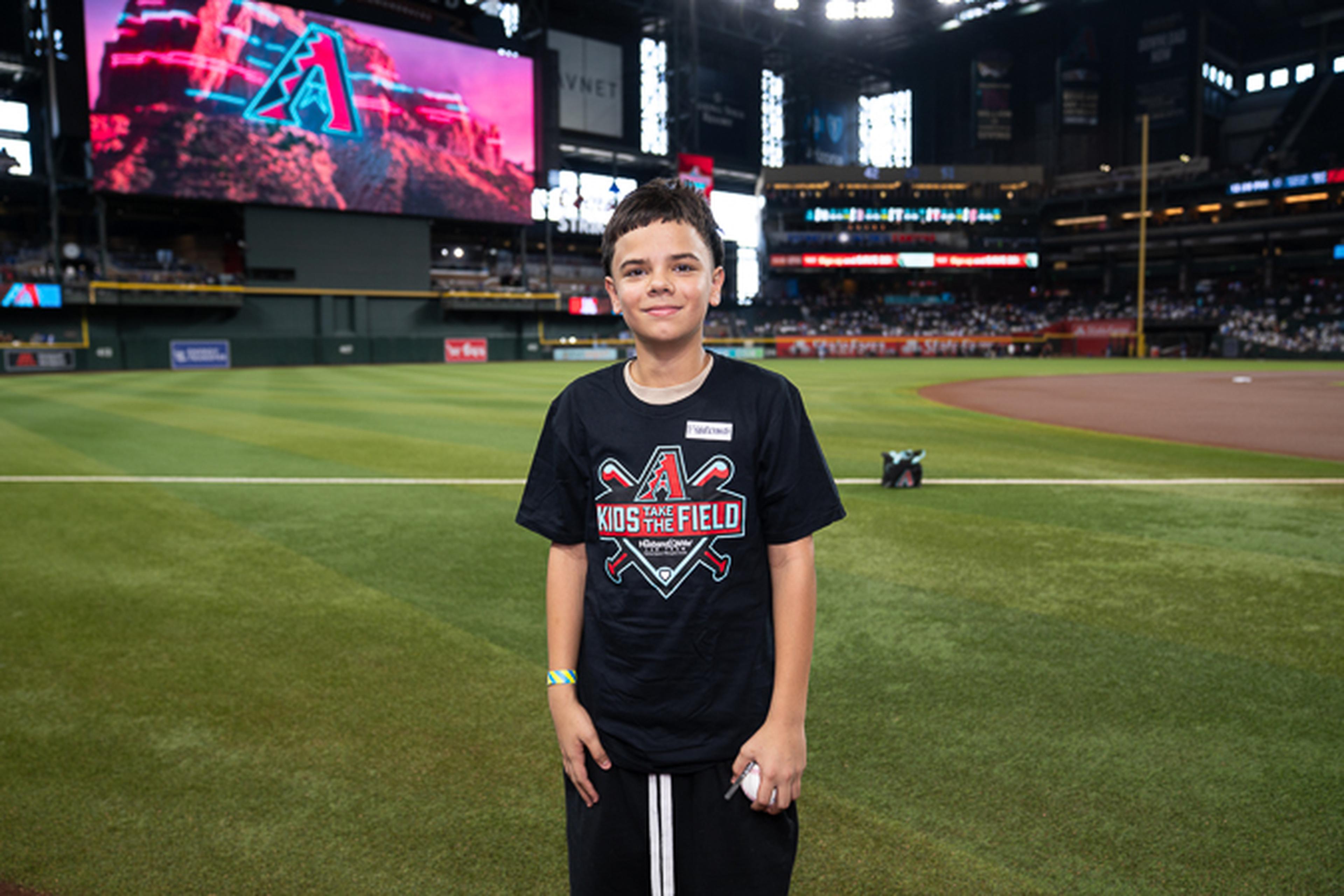 A young Kids Take the Field participant stands proudly on Chase Field, enjoying a once-in-a-lifetime opportunity at the home of the Arizona Diamondbacks.