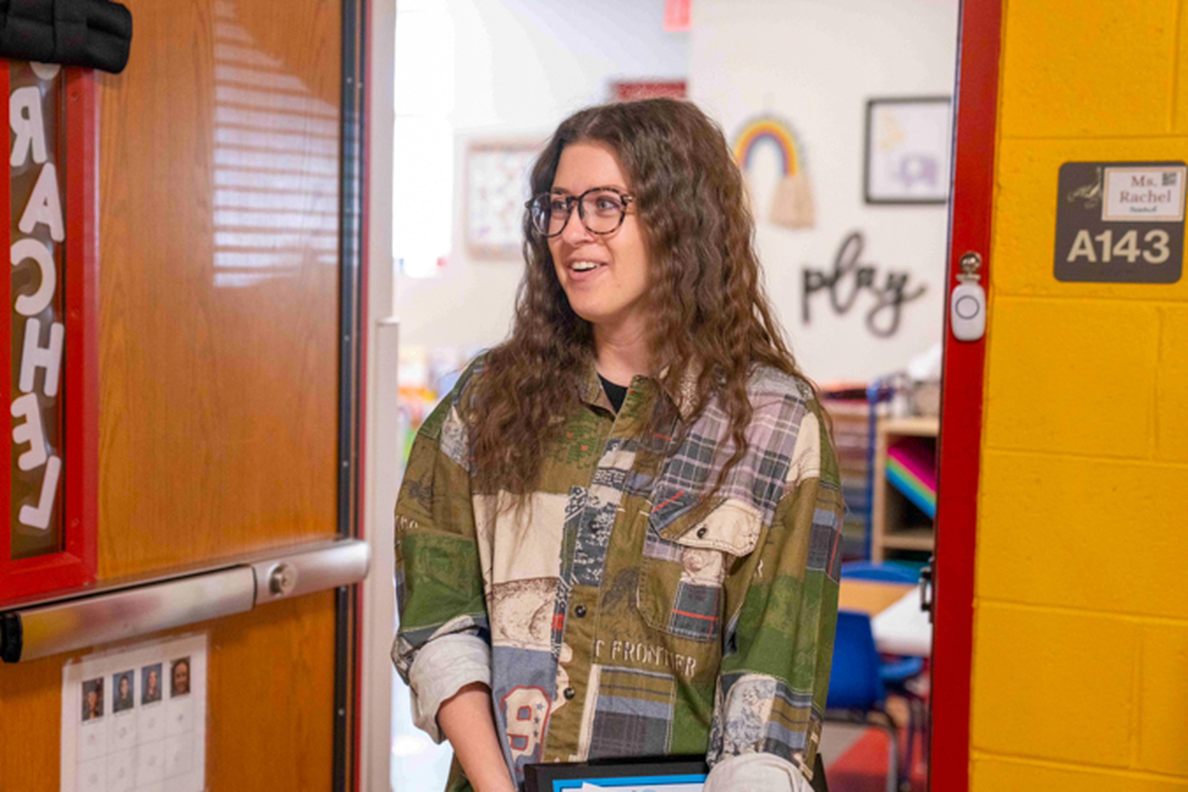 Woman in a school doorway, smiling and talking