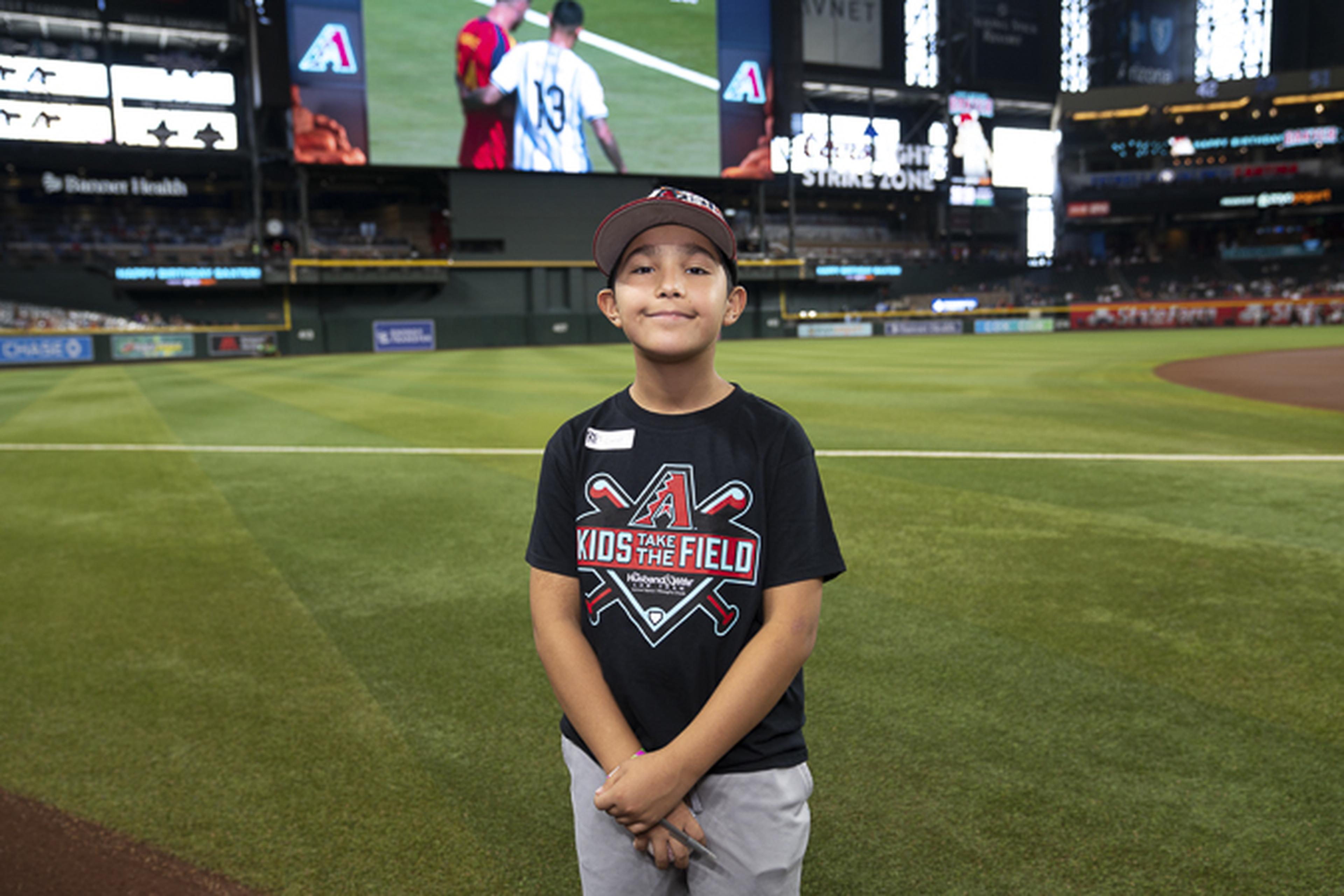 A Husband & Wife Law Team Kids Take the Field winner stands on Chase Field with big-league dreams and a smile, enjoying an unforgettable day where future stars shine.