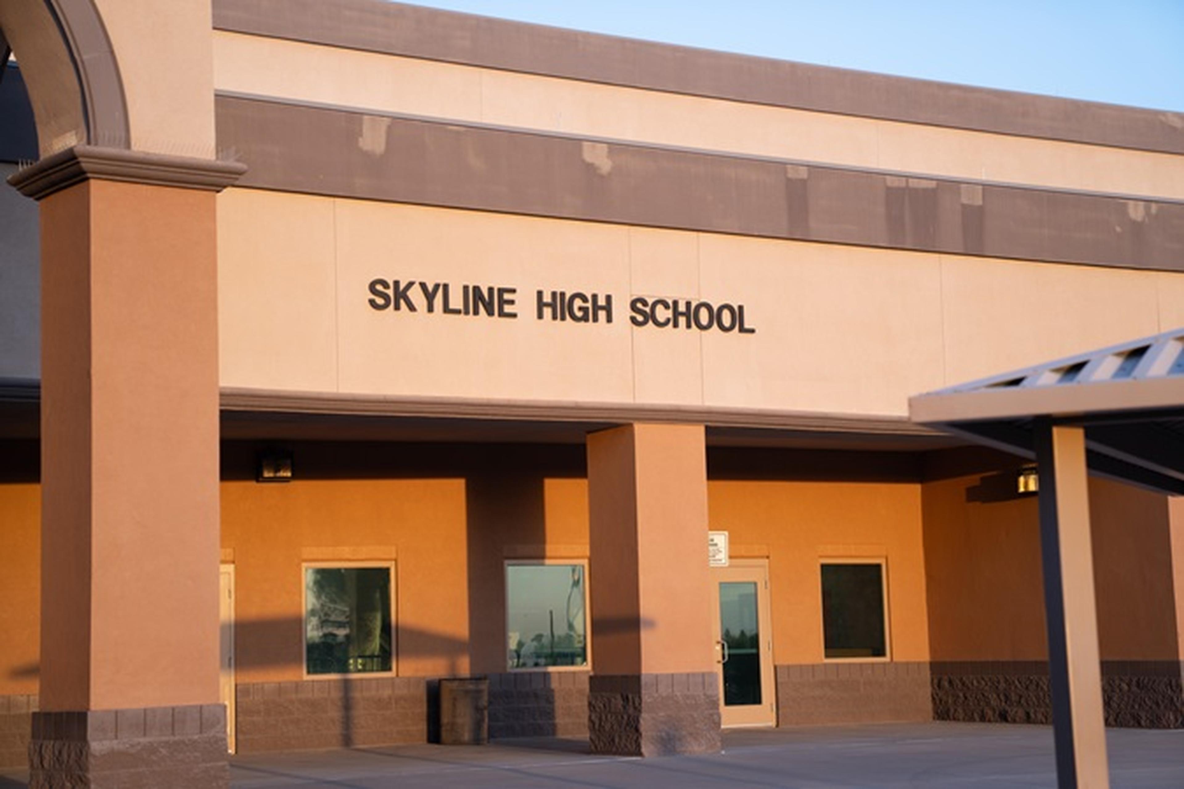 Exterior of Skyline High School at 845 S Crismon Rd in Mesa, AZ, featuring beige and brown walls, large windows, and its name displayed above the entrance.