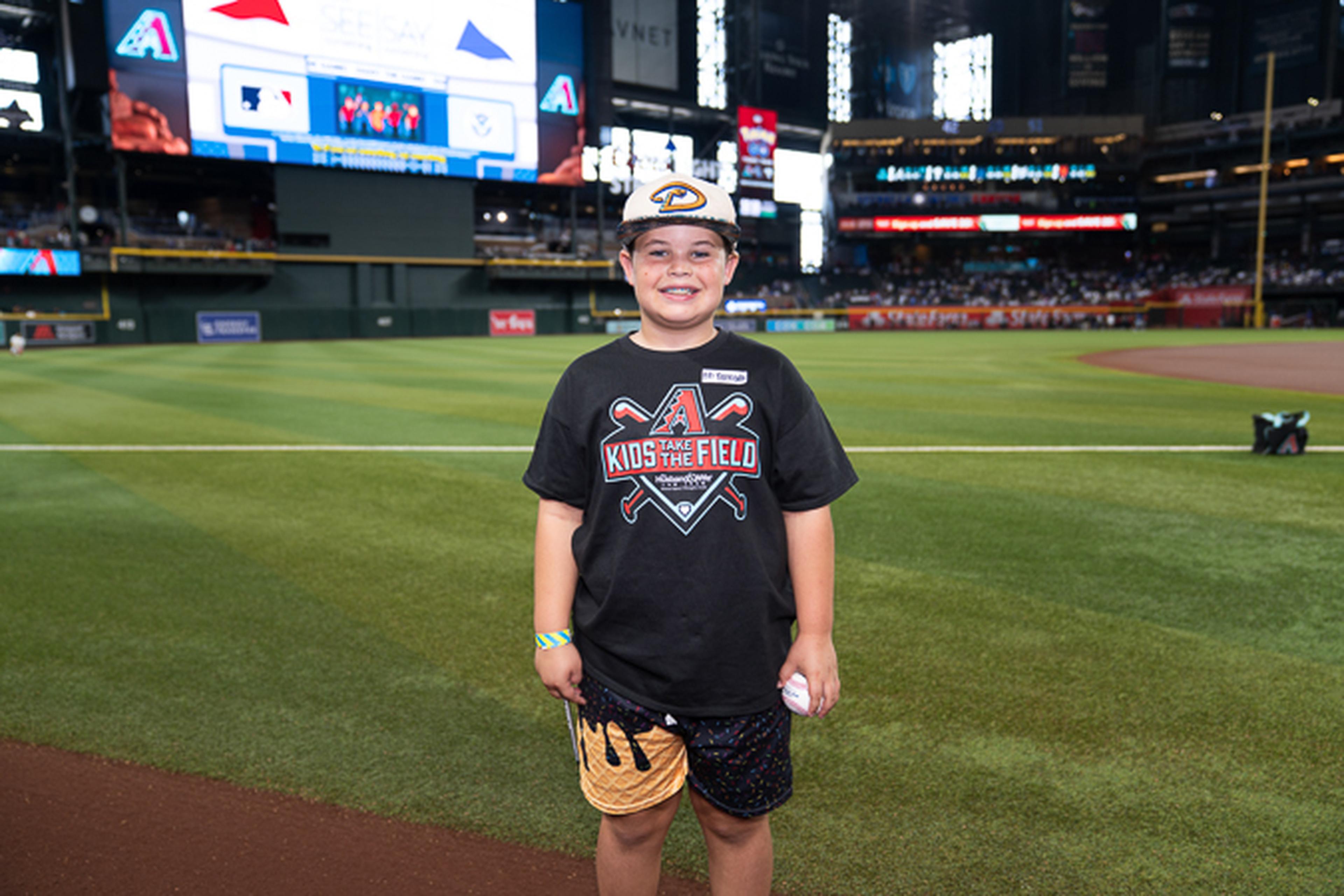 A young Kids Take the Field participant smiles on Chase Field, enjoying a memorable day at the home of the Arizona Diamondbacks.
