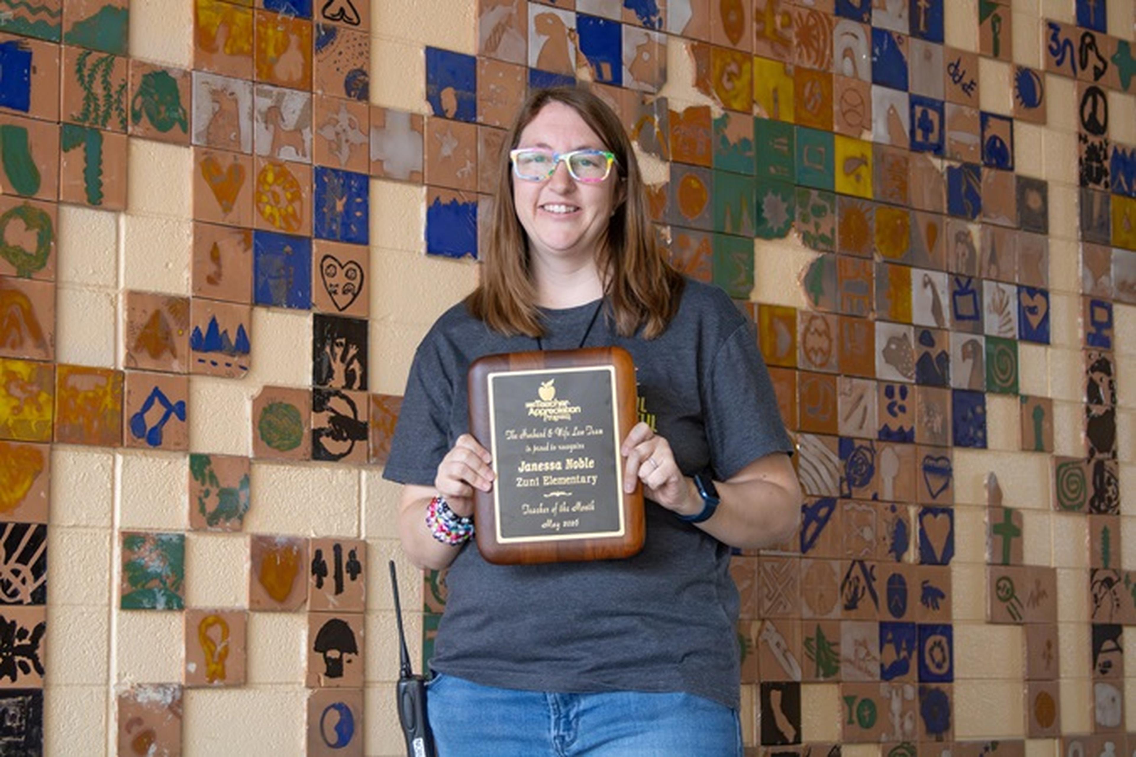 Close-up of Ms. Noble smiling as she holds The Husband & Wife Law Team’s Teacher Appreciation Award.