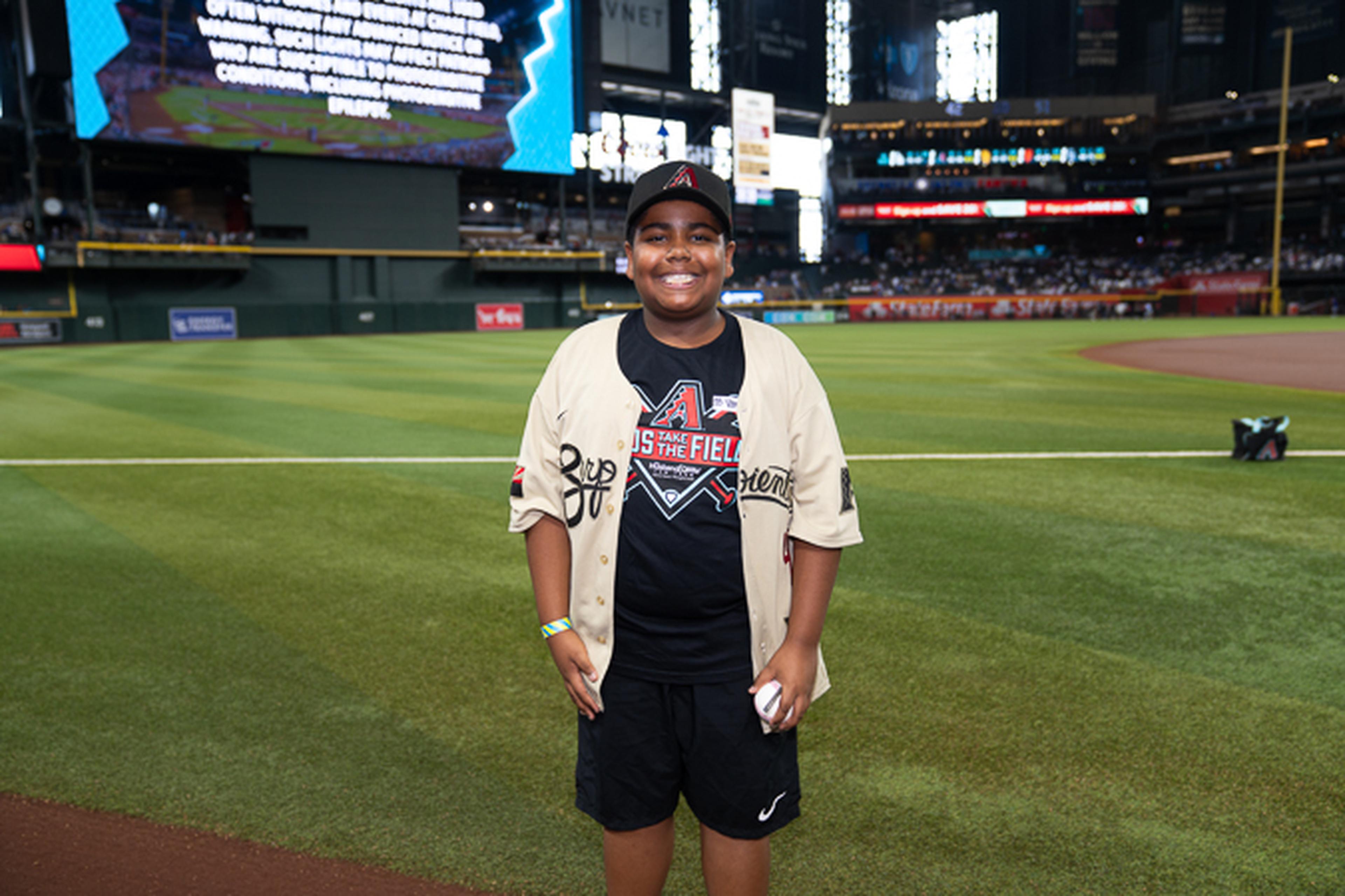 A young Kids Take the Field winner smiles on Chase Field, soaking in a once-in-a-lifetime experience at the home of the Arizona Diamondbacks.