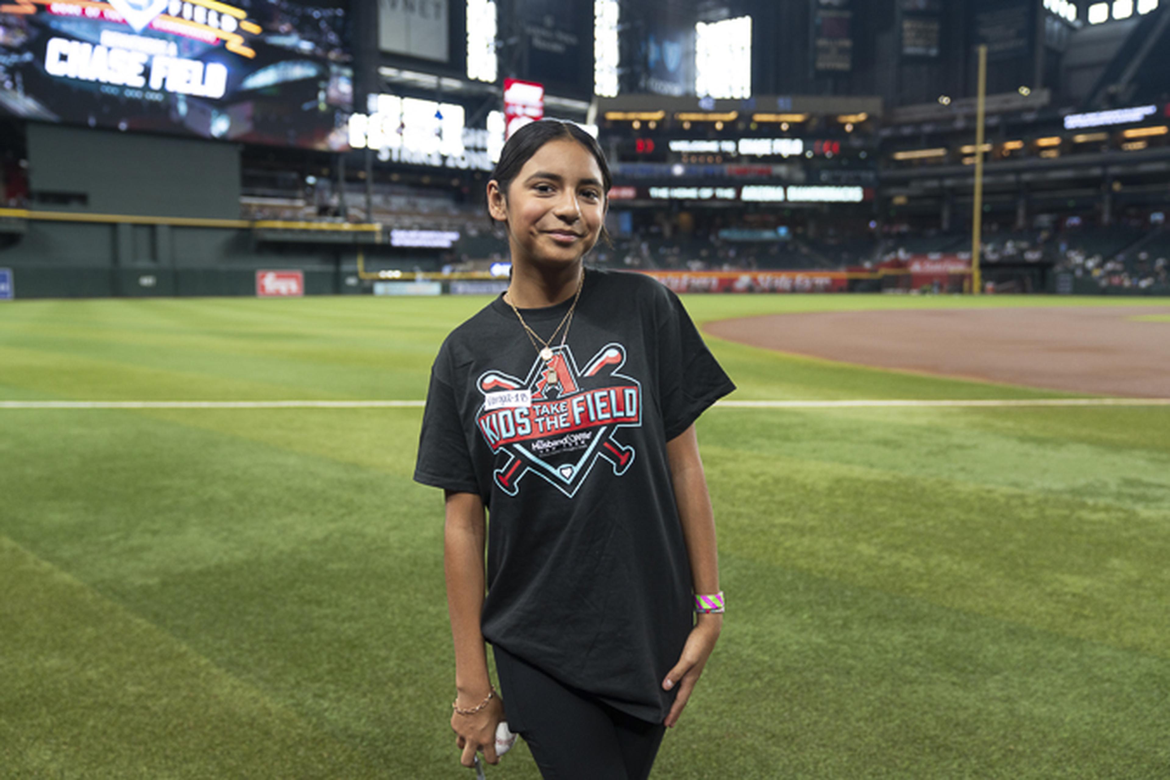 A Kids Take the Field winner stands on the field at Chase Field, taking in a once-in-a-lifetime experience at the home of the Arizona Diamondbacks.