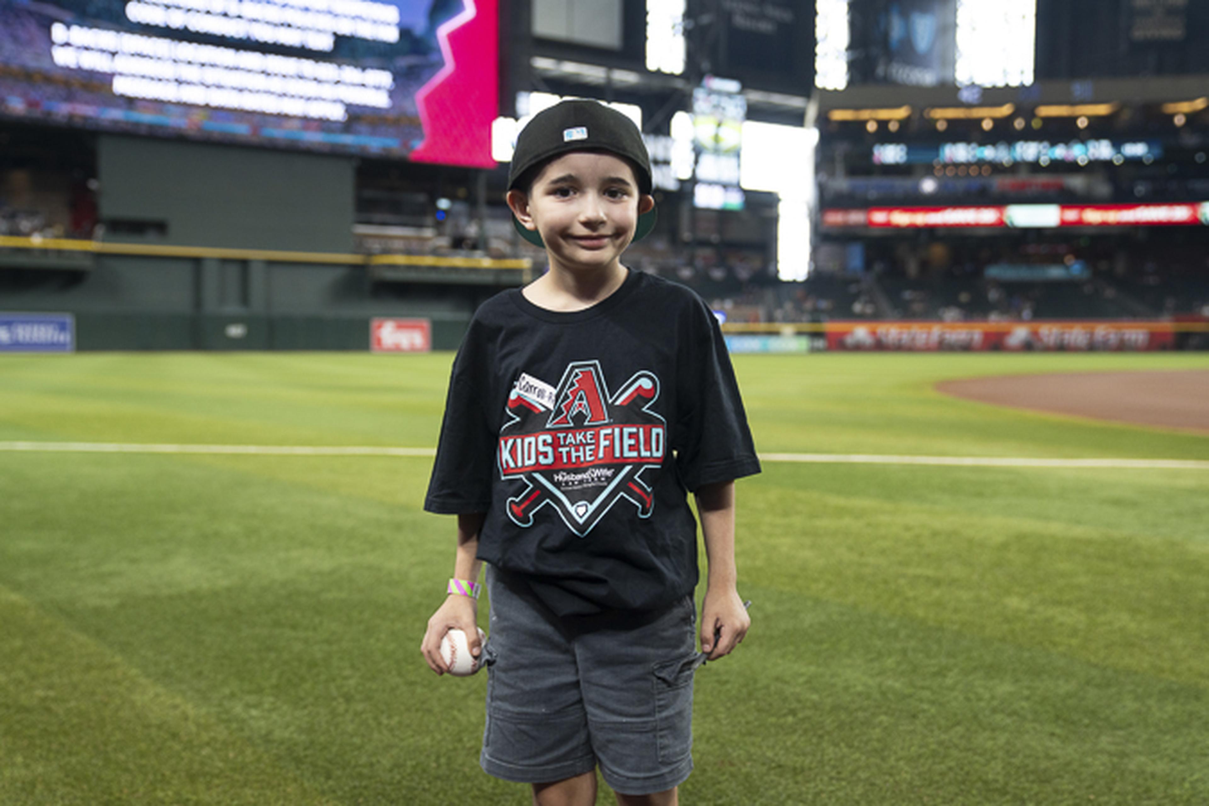 A young baseball fan proudly holds his baseball while enjoying a memorable day on the field, capturing the excitement of America’s favorite pastime.