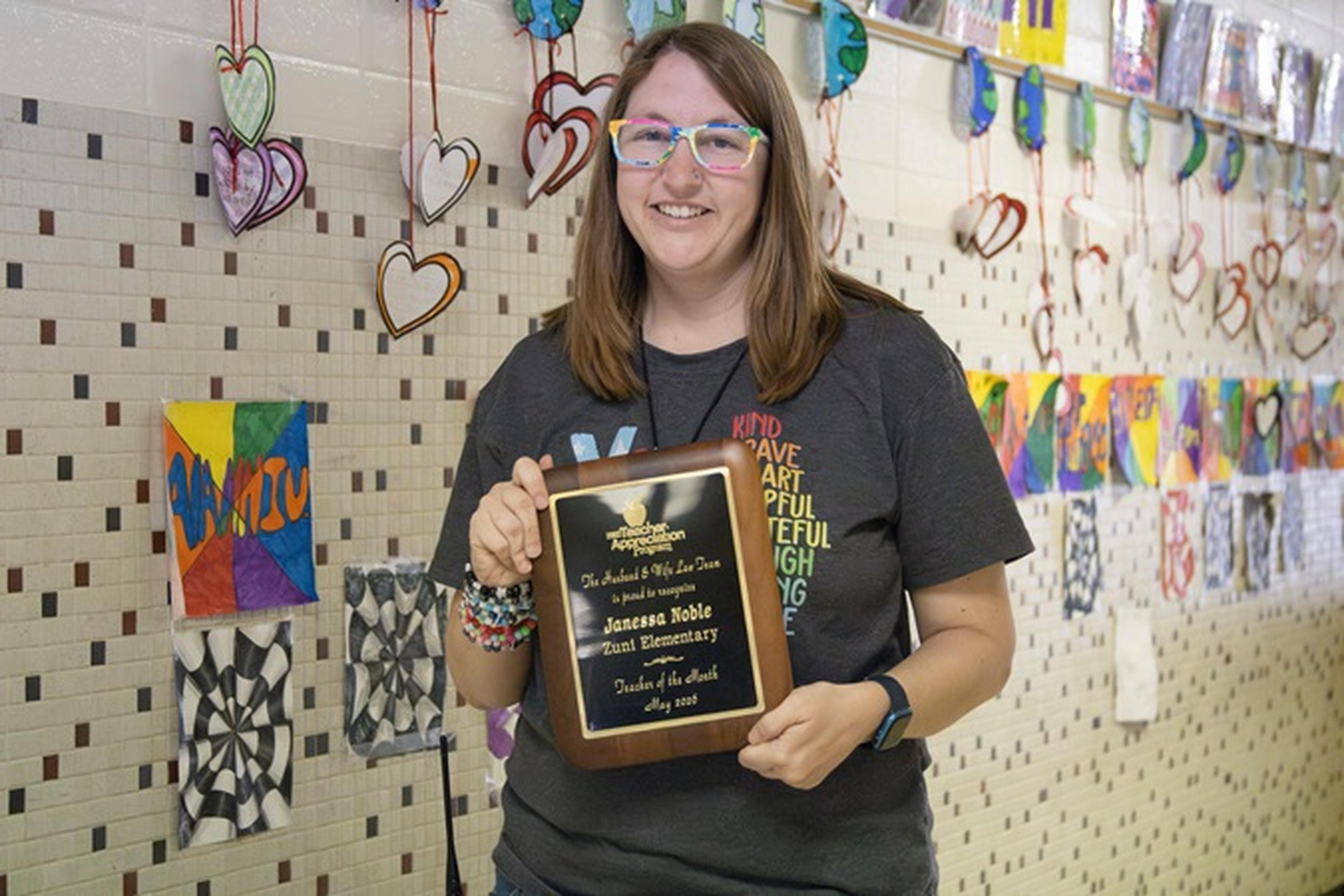 Ms. Noble of Zuni Technology & Communication Magnet School holds a plaque and a $500 “Teacher of the Month” check.