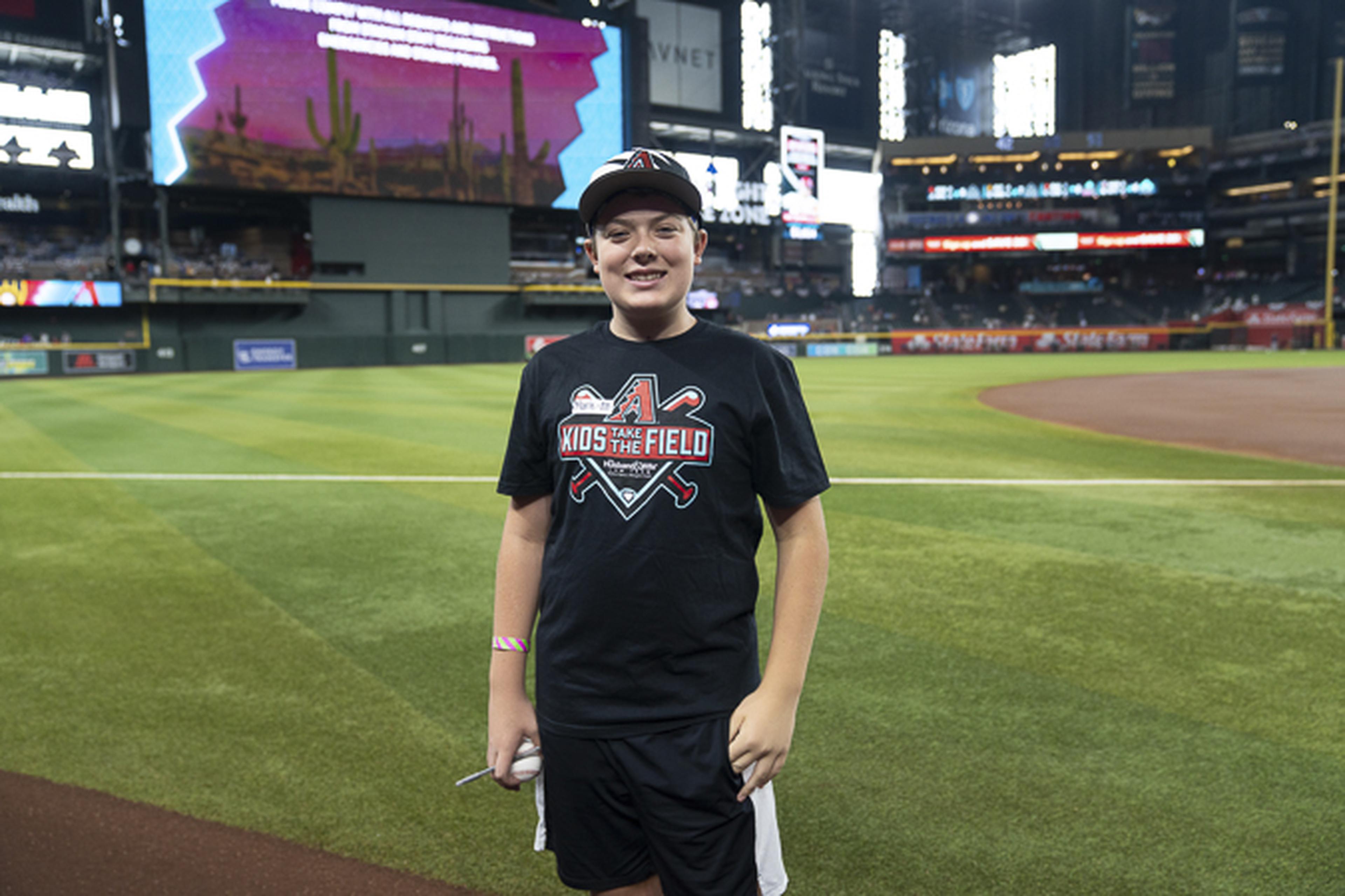 A young fan smiles on the field during the Kids Take the Field experience, enjoying a memorable day at the ballpark.
