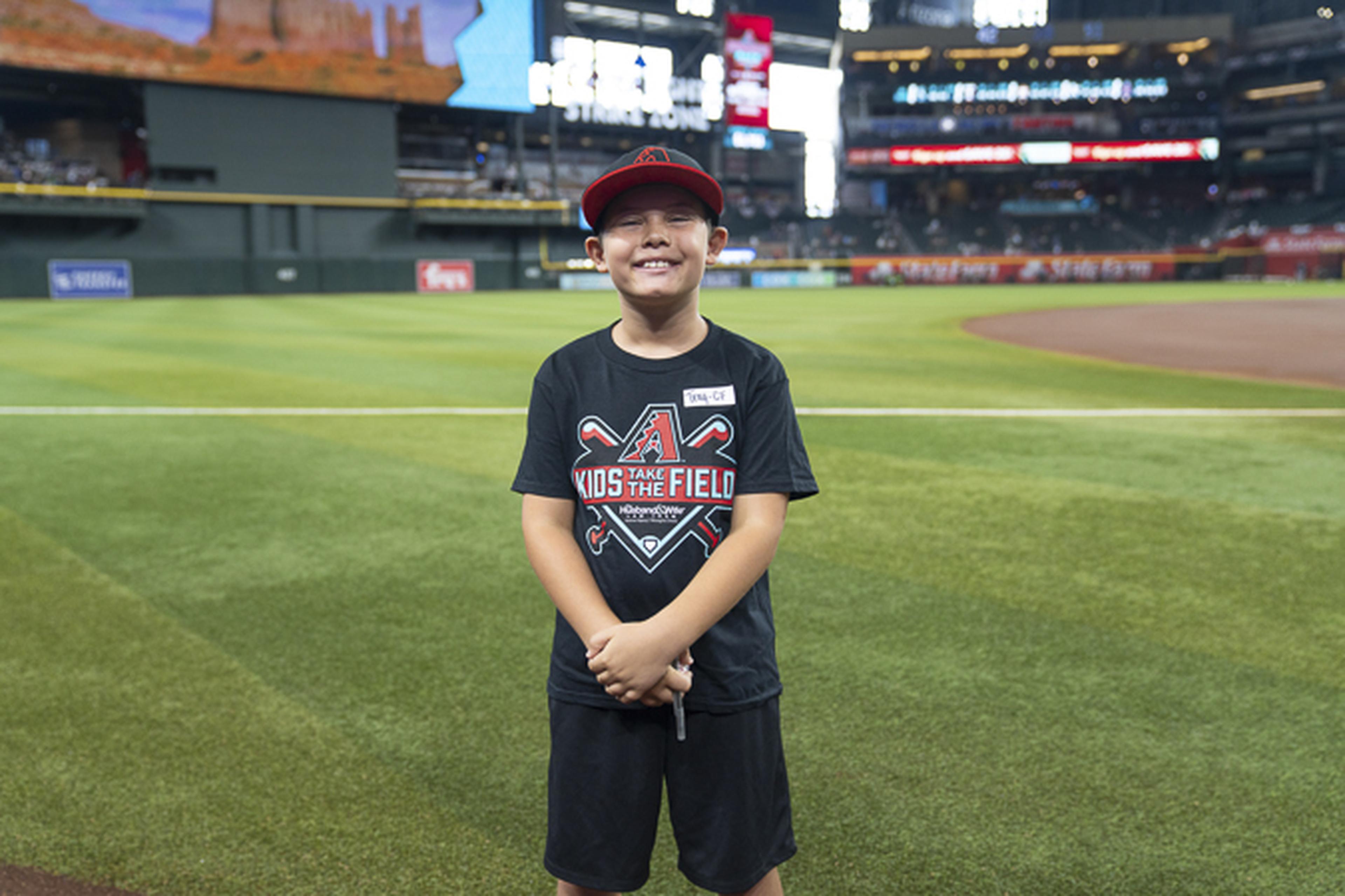 A young participant in the Take Kids to the Field program smiles on the field at Chase Field, enjoying a memorable day at the home of the Arizona Diamondbacks.