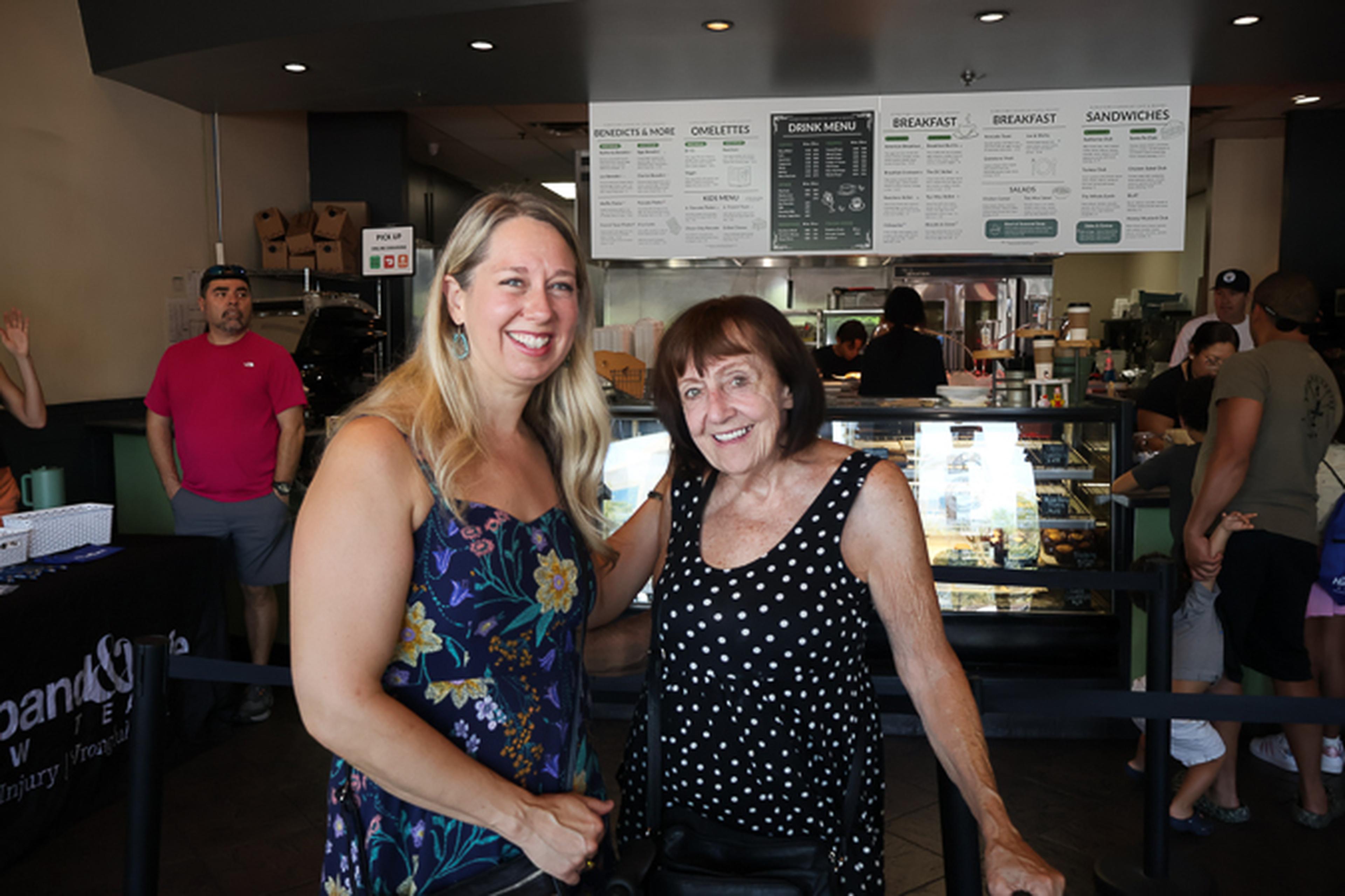 Two attendees share a smile inside Downtown Chandler Cafe & Bakery during the Husband & Wife Law Team’s HEART event, enjoying a morning of community connection and local favorites.