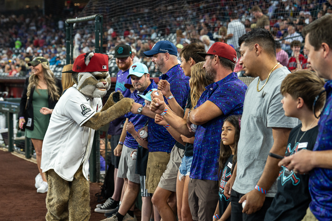 Baxter, the Arizona Diamondbacks mascot, interacts with a young fan holding a baseball at the Kids Take The Field event.