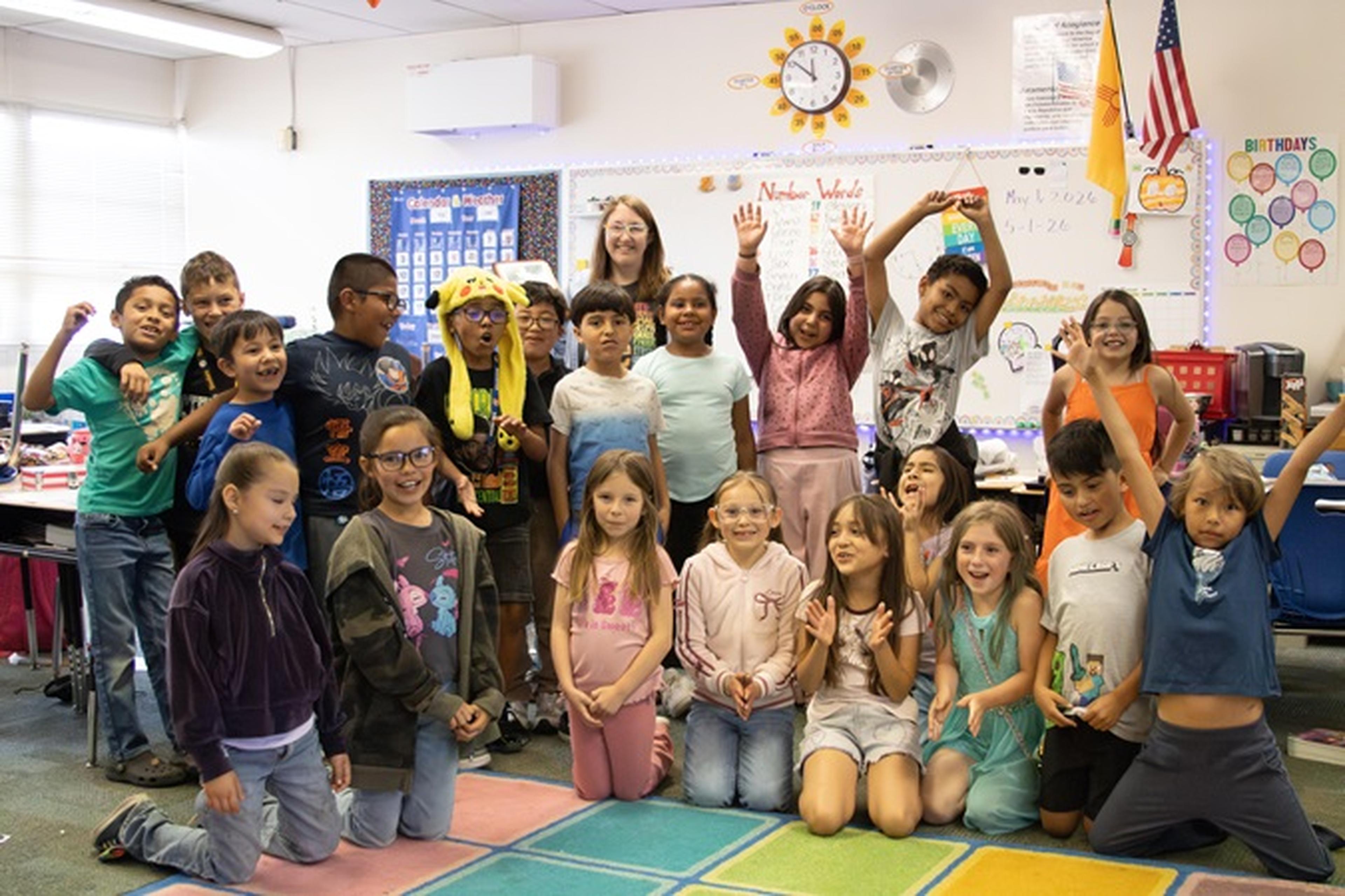 Students from Zuni Technology & Communication Magnet School pose with Ms. Noble in a colorful classroom.
