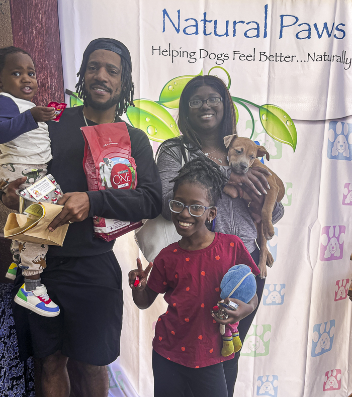 A happy family poses with their newly adopted dog at the Husband & Wife Law Team's HALO Adoption Event, celebrating a fresh start with pet supplies, toys, and plenty of smiles.
