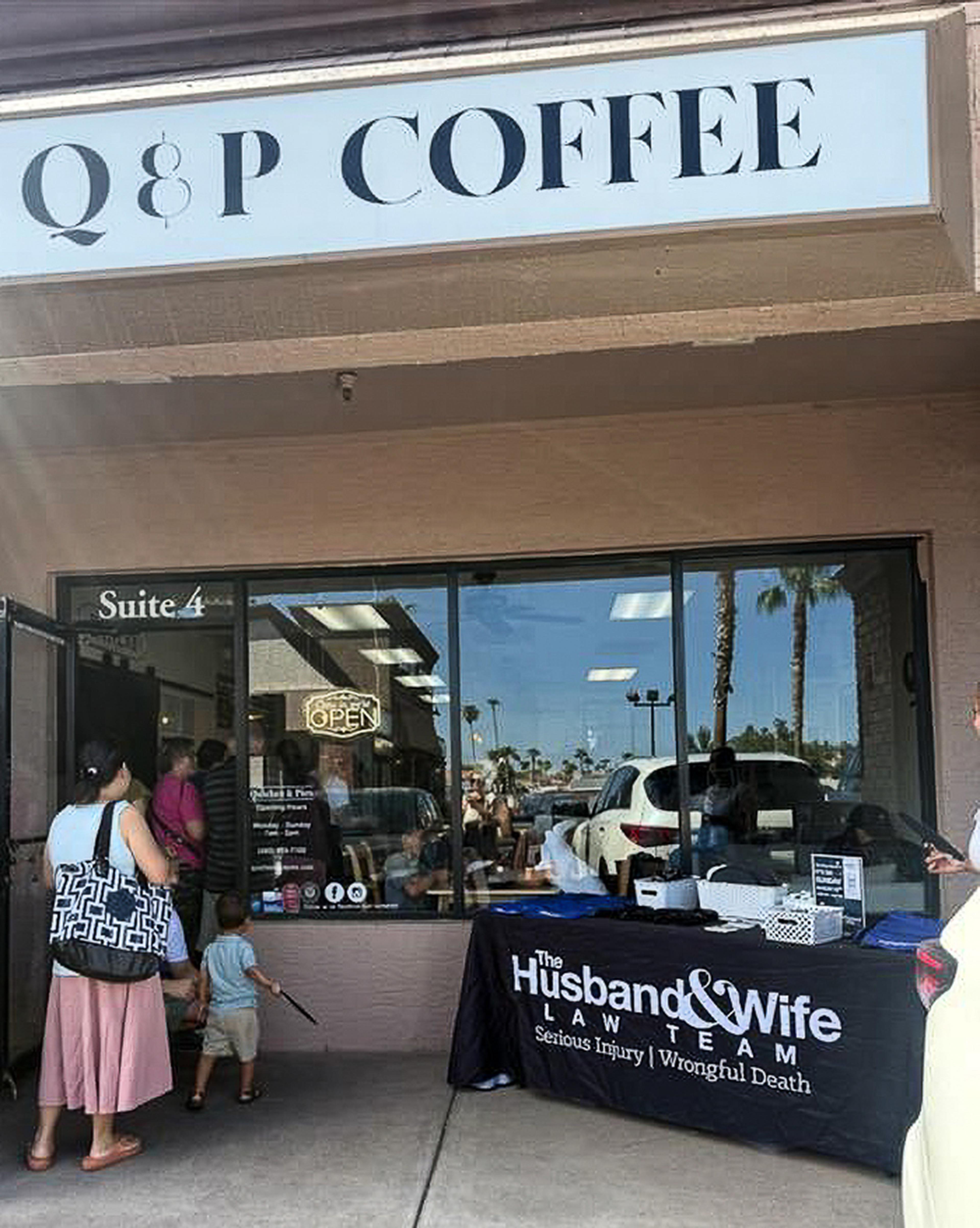 A Husband & Wife Law Team information table welcomes visitors outside Quiches & Pies Bakery, providing resources and connecting with the community during a local HEART event.