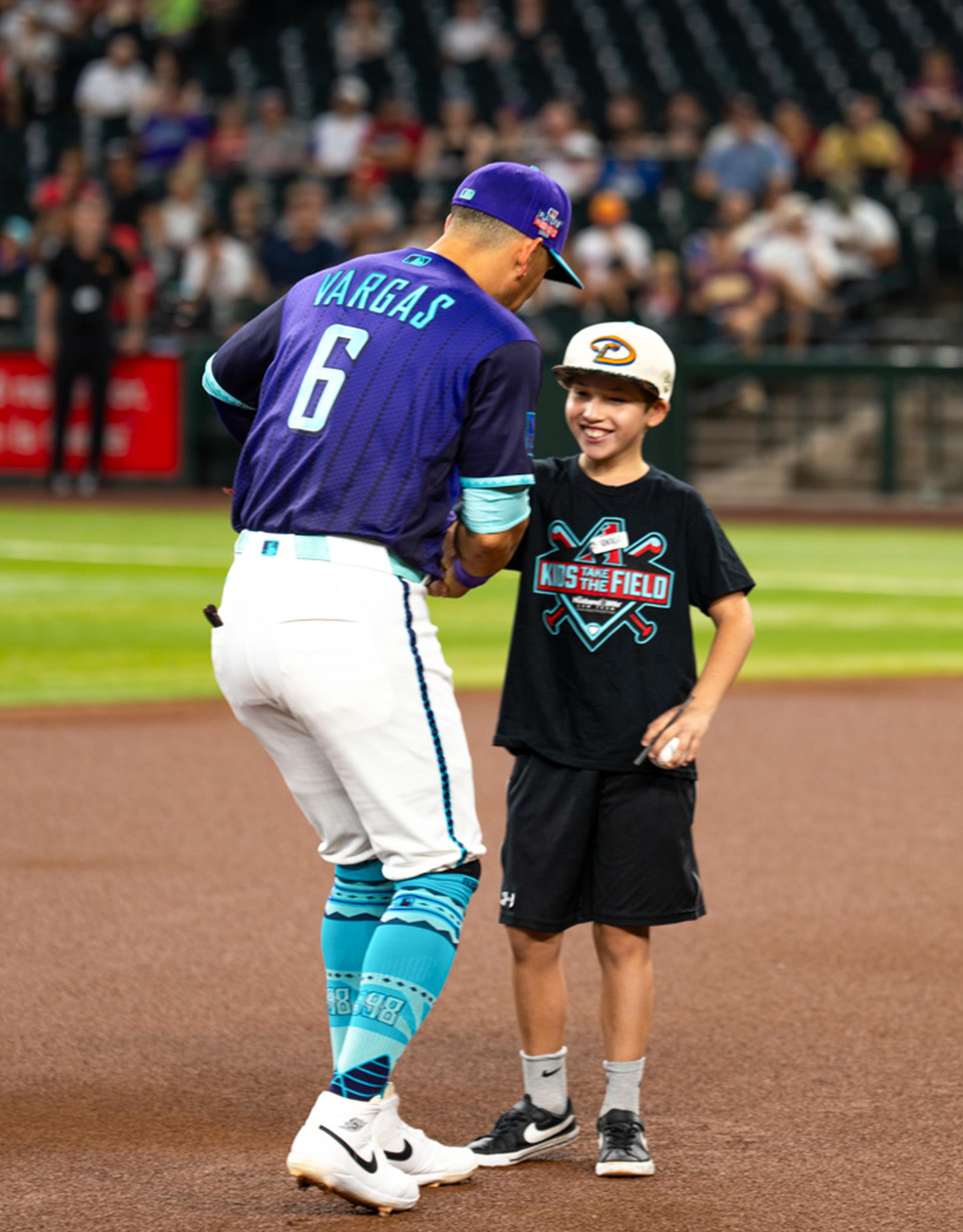 A young Kids Take the Field participant shares a memorable handshake with an Arizona Diamondbacks player, enjoying a once-in-a-lifetime moment on the field before the game.