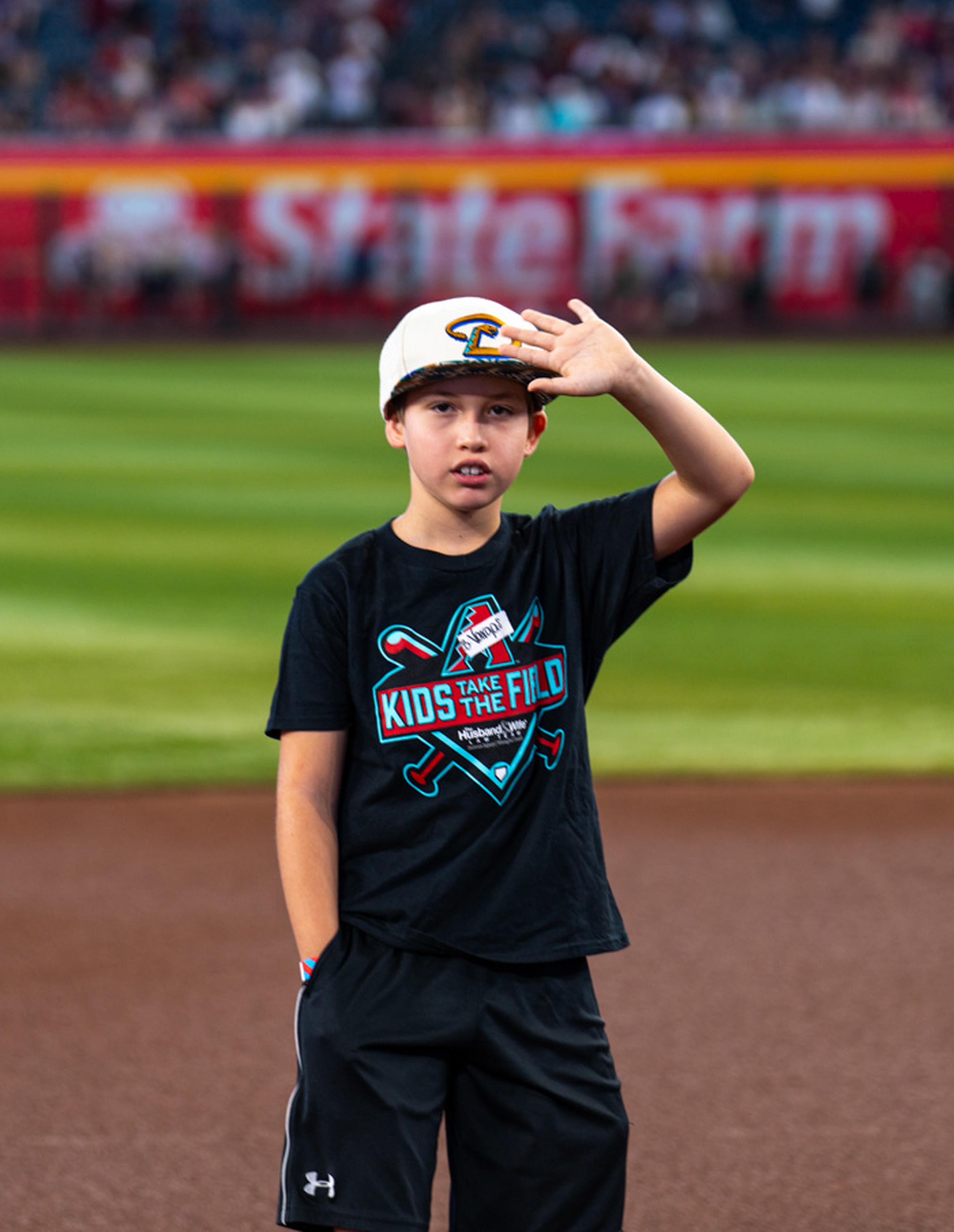 A young Kids Take the Field participant shades his eyes from the sun while taking in the excitement of standing on the field at Chase Field, creating a memory he'll never forget.