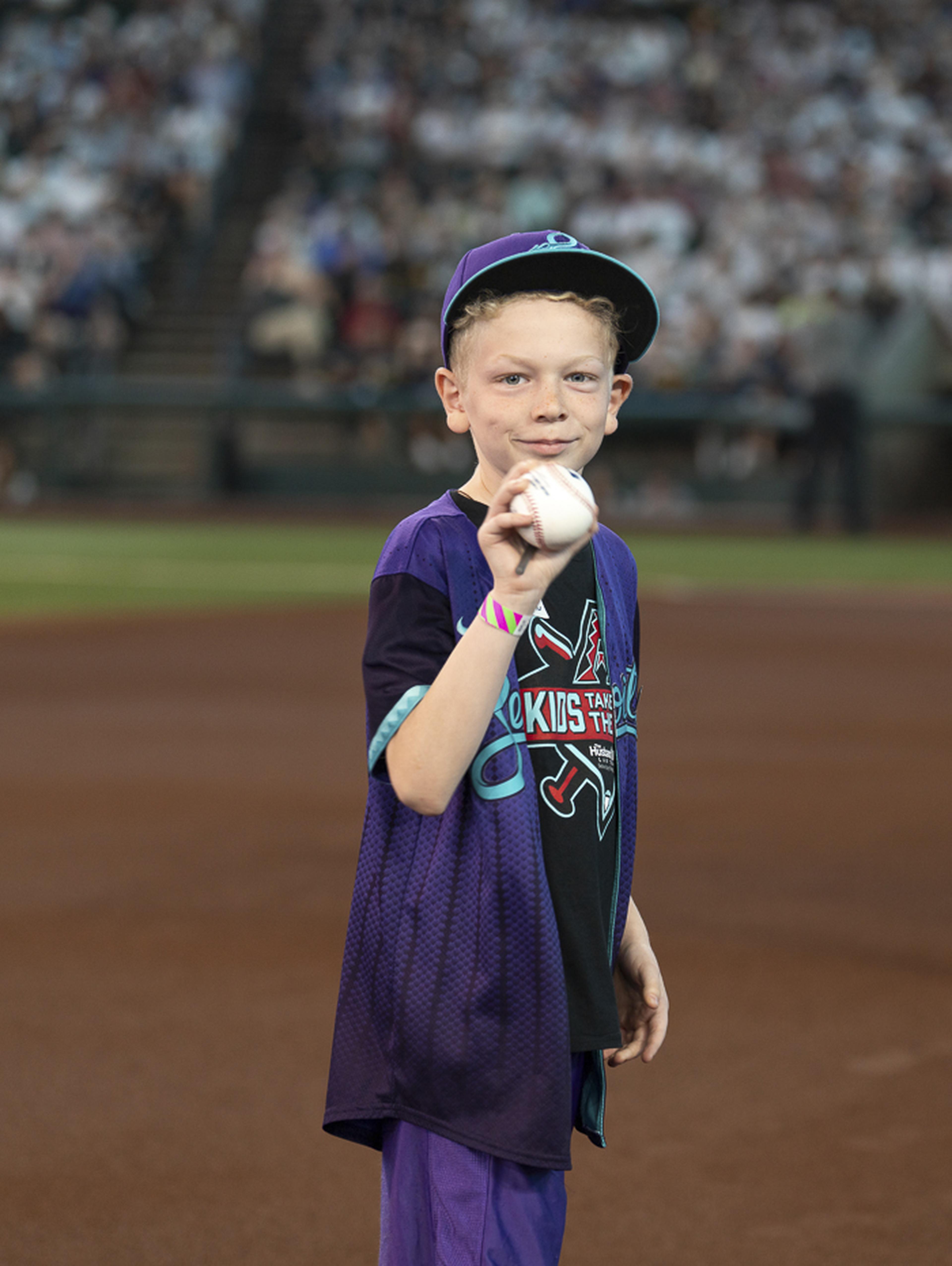 With a baseball in hand and a smile on his face, a young fan enjoys his moment in the spotlight during the Kids Take the Field experience, creating memories that will last long after game day.