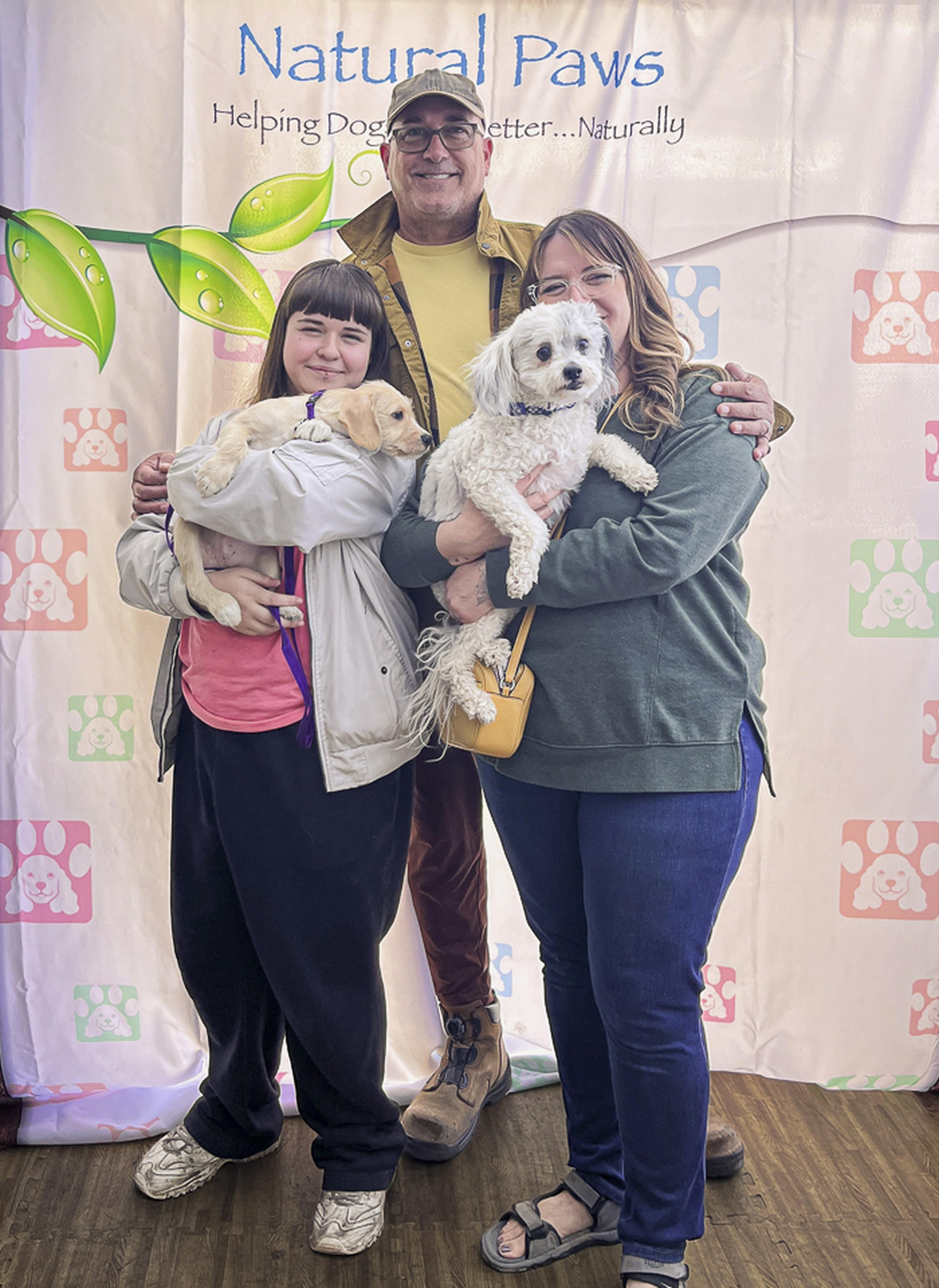 A family and their two dogs pose together at the Husband & Wife Law Team’s HALO Adoption Event, celebrating the special bond between pets and the people who love them.