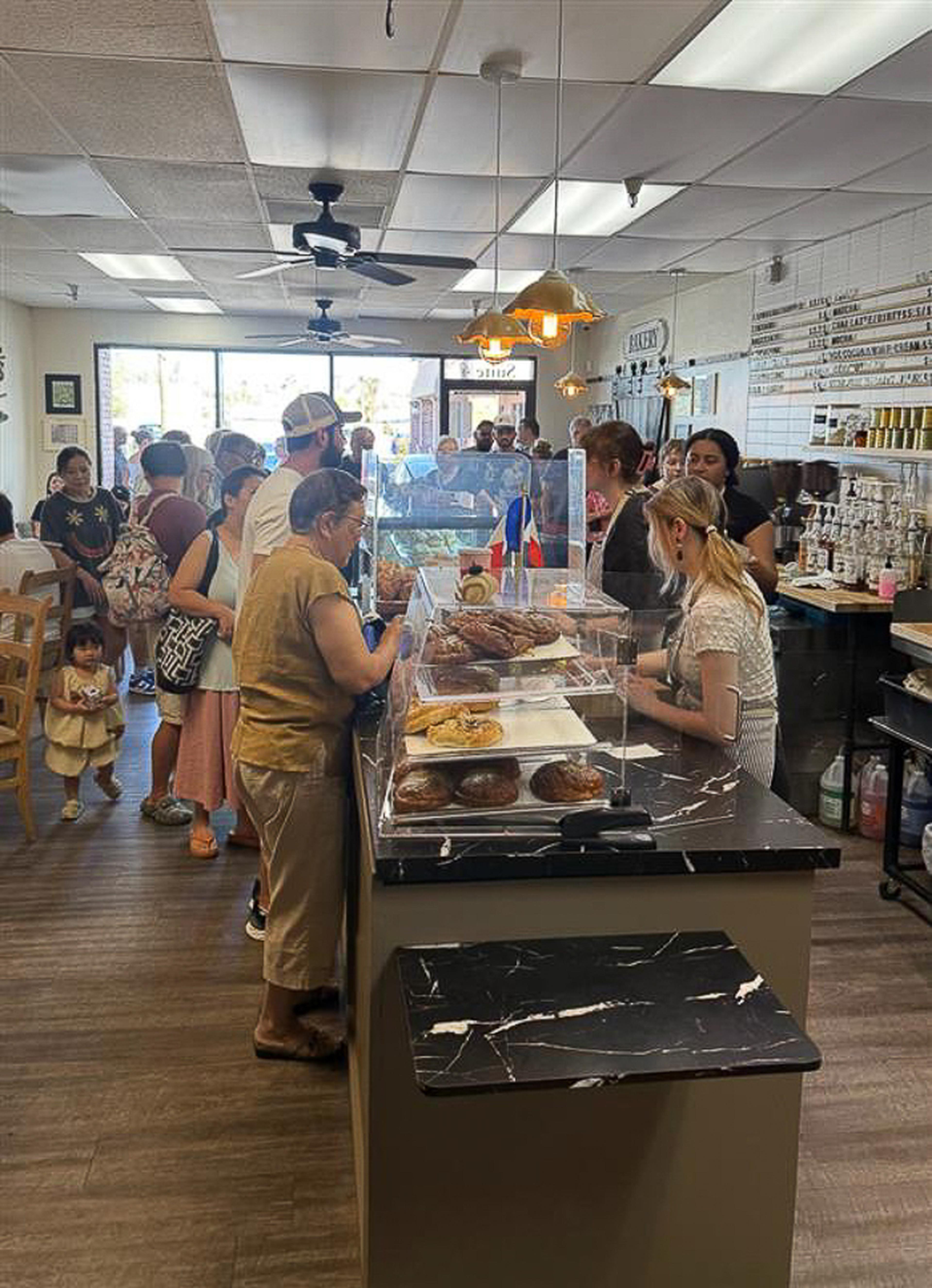 Guests line up inside Quiches & Pies Bakery as fresh pastries fill the display case, creating a warm and welcoming atmosphere during the Husband & Wife Law Team’s HEART event.
