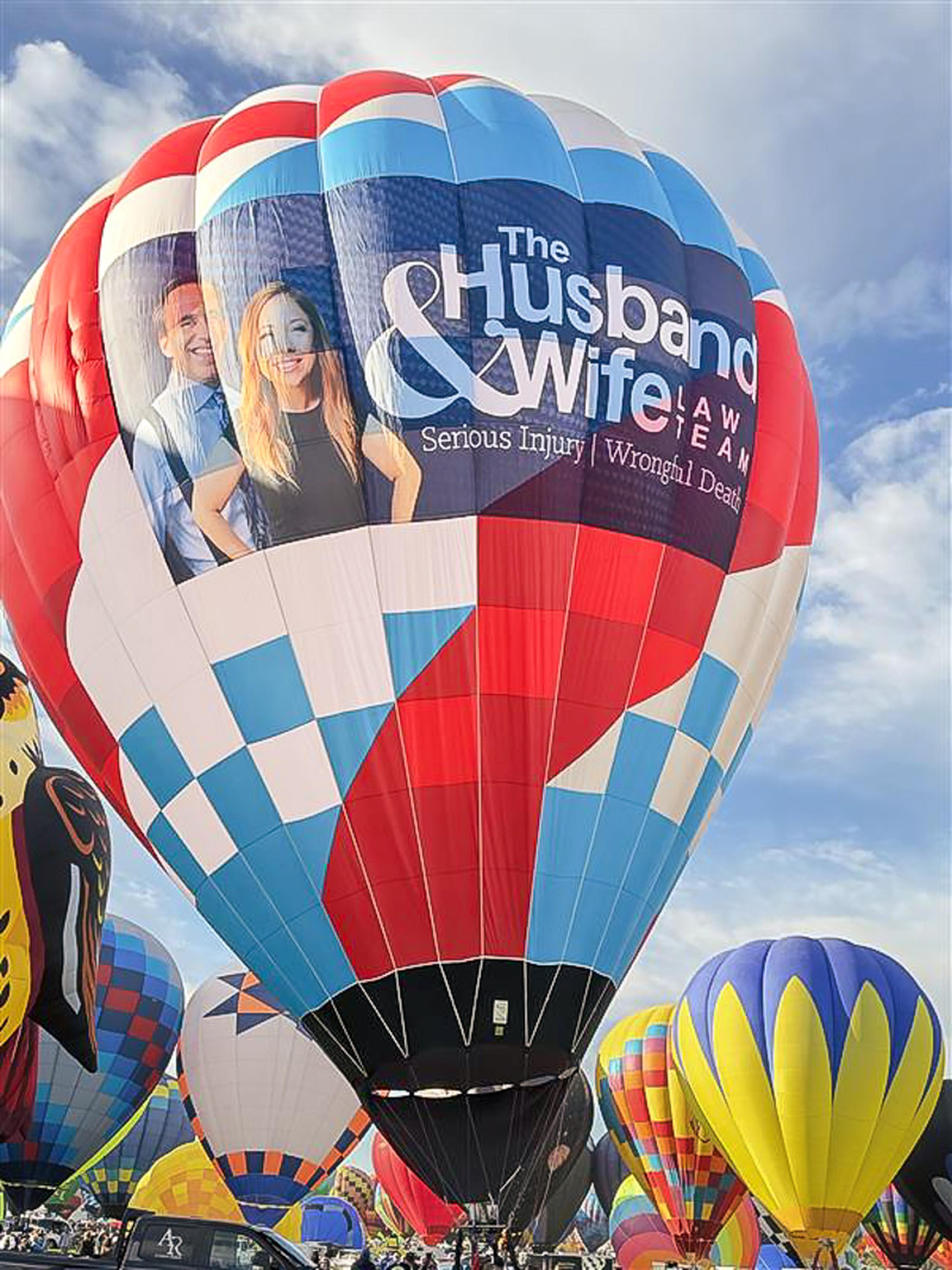 A picture-perfect Balloon Fiesta moment as the Husband & Wife Law Team balloon joins a vibrant display of balloons under the New Mexico sky.