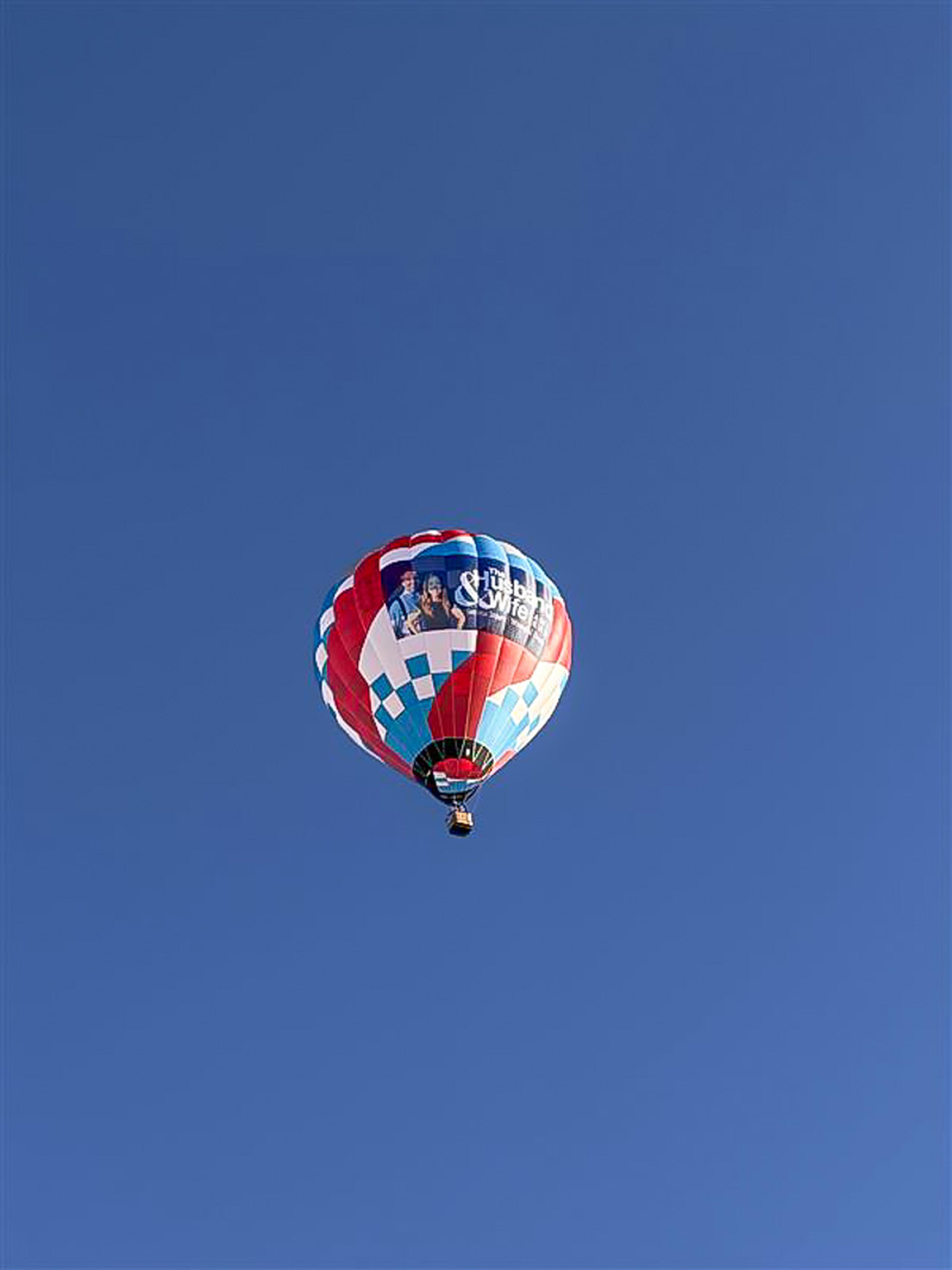 HWLT takes to the skies! The vibrant red, white, and blue Husband & Wife Law Team balloon soars above Albuquerque during the Balloon Fiesta.