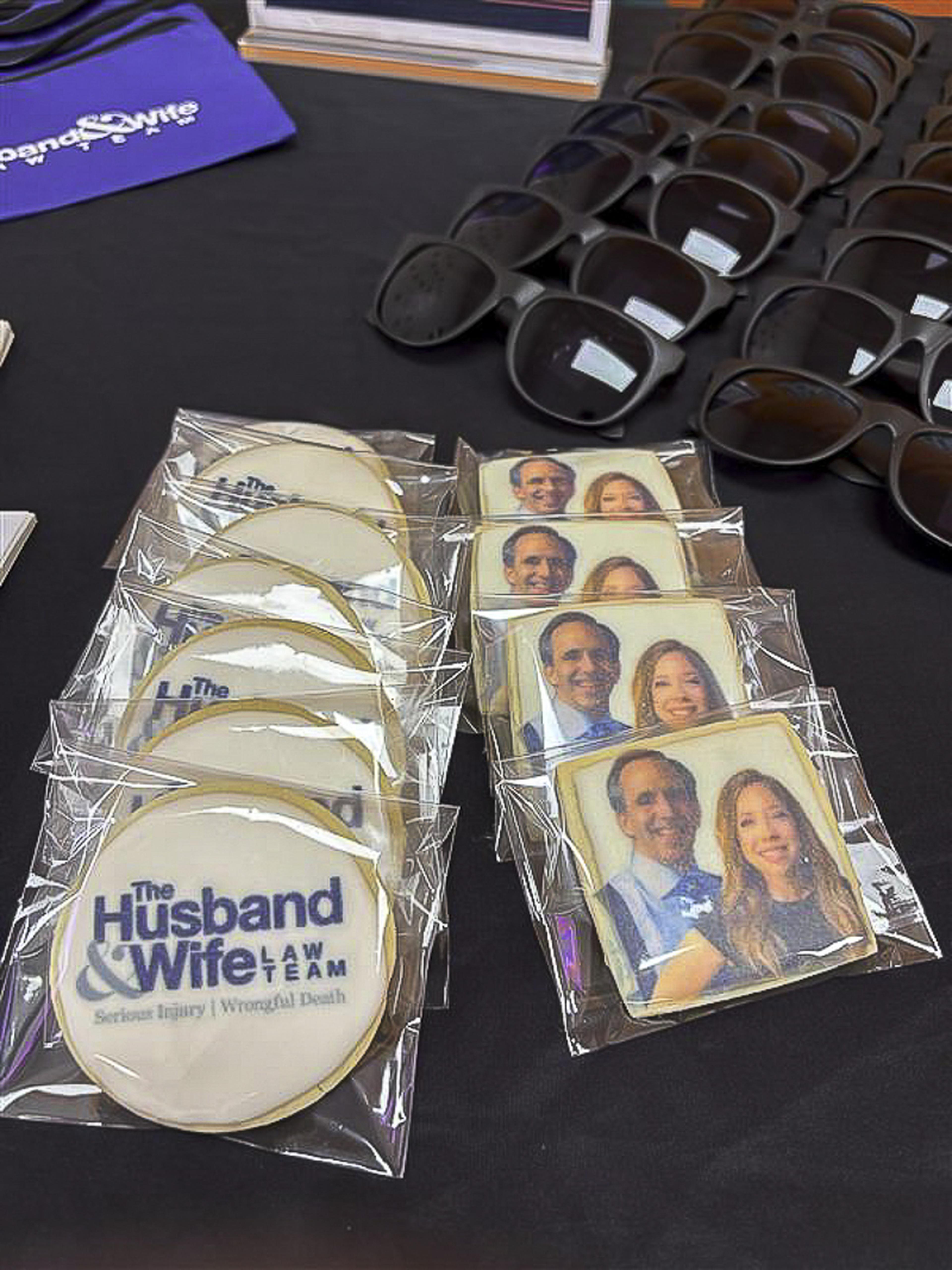 Custom cookies featuring Mark and Alexis Breyer are displayed alongside Husband & Wife Law Team sunglasses during a fun-filled HEART event.