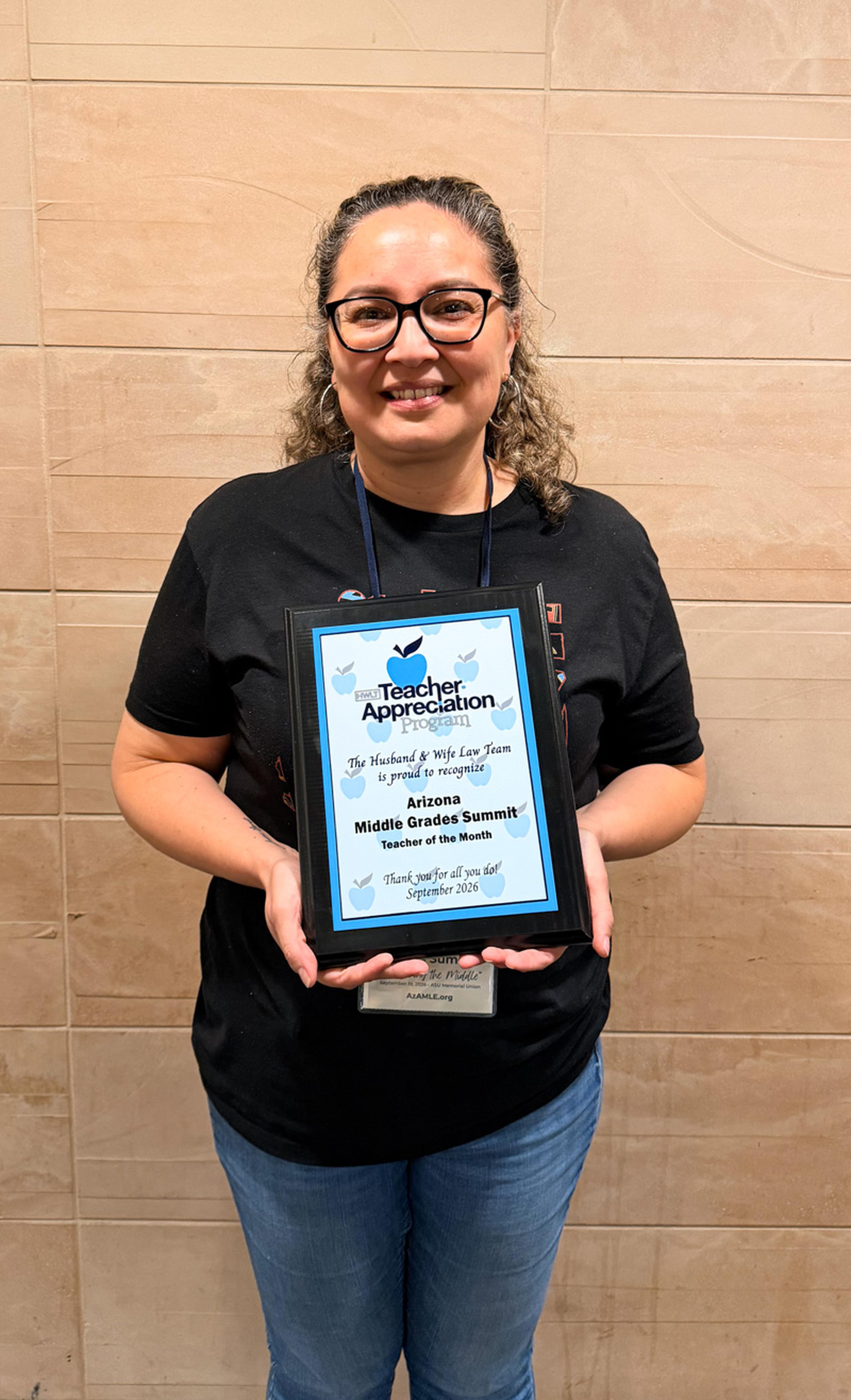 Ms. Lozano proudly displays her Teacher of the Month award, recognizing her dedication, leadership, and positive impact on students every day.