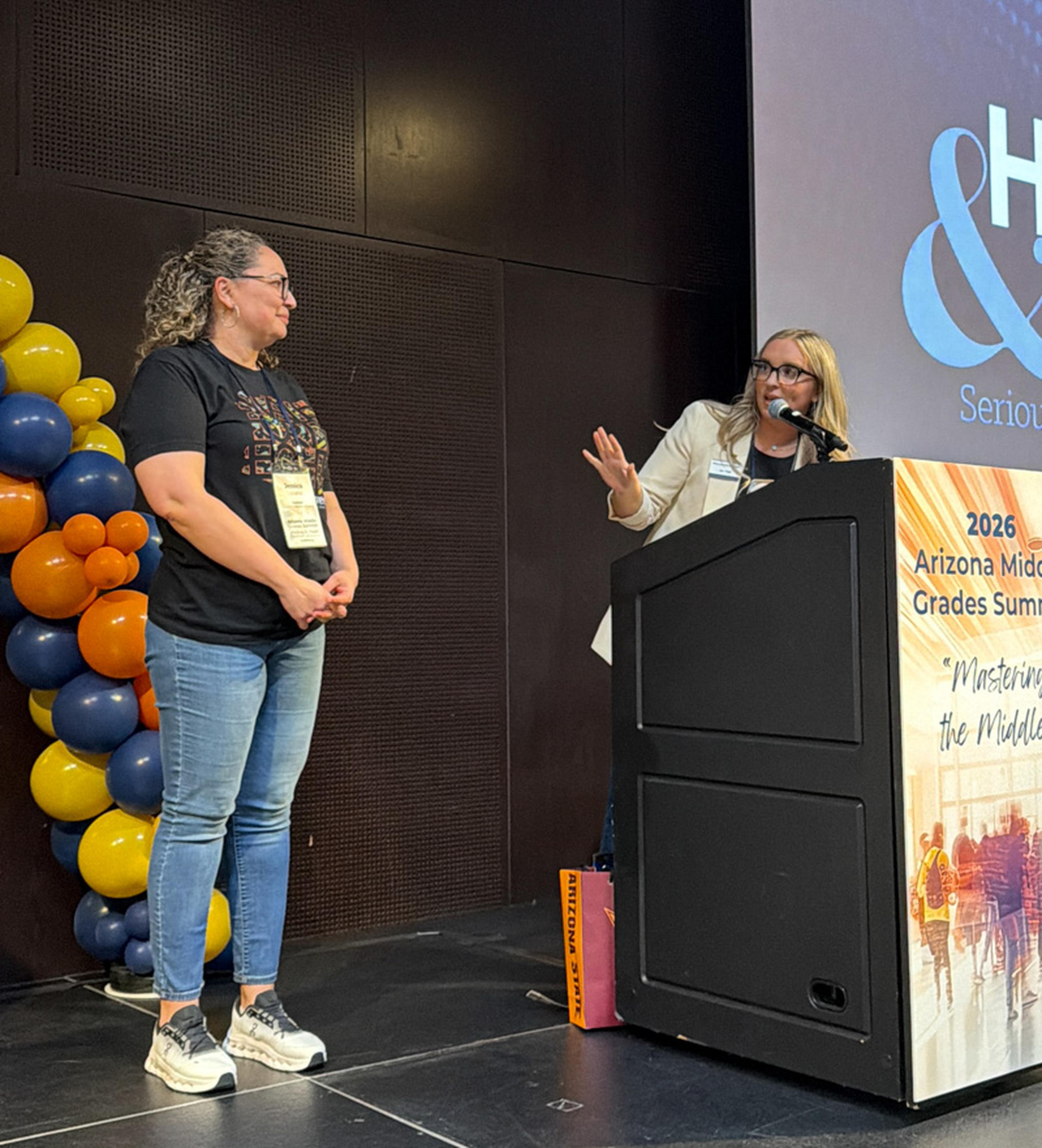 Jen from the Husband & Wife Law Team recognizes Ms. Lozano at the Arizona Middle Grades Summit, celebrating her Teacher of the Month award and dedication to student success.