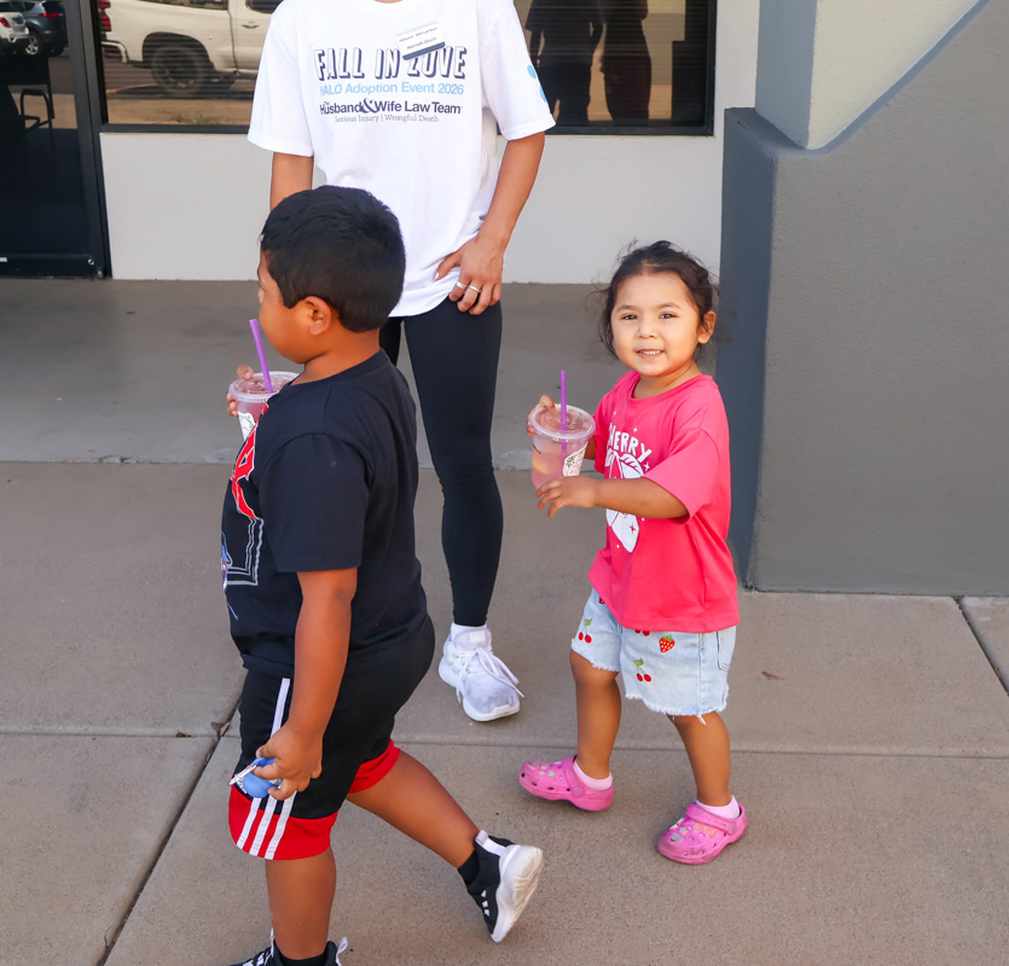 Two young attendees enjoy a day at the Husband & Wife Law Team’s HALO Adoption Event, walking alongside family members and taking in the excitement of supporting pets in search of loving homes.